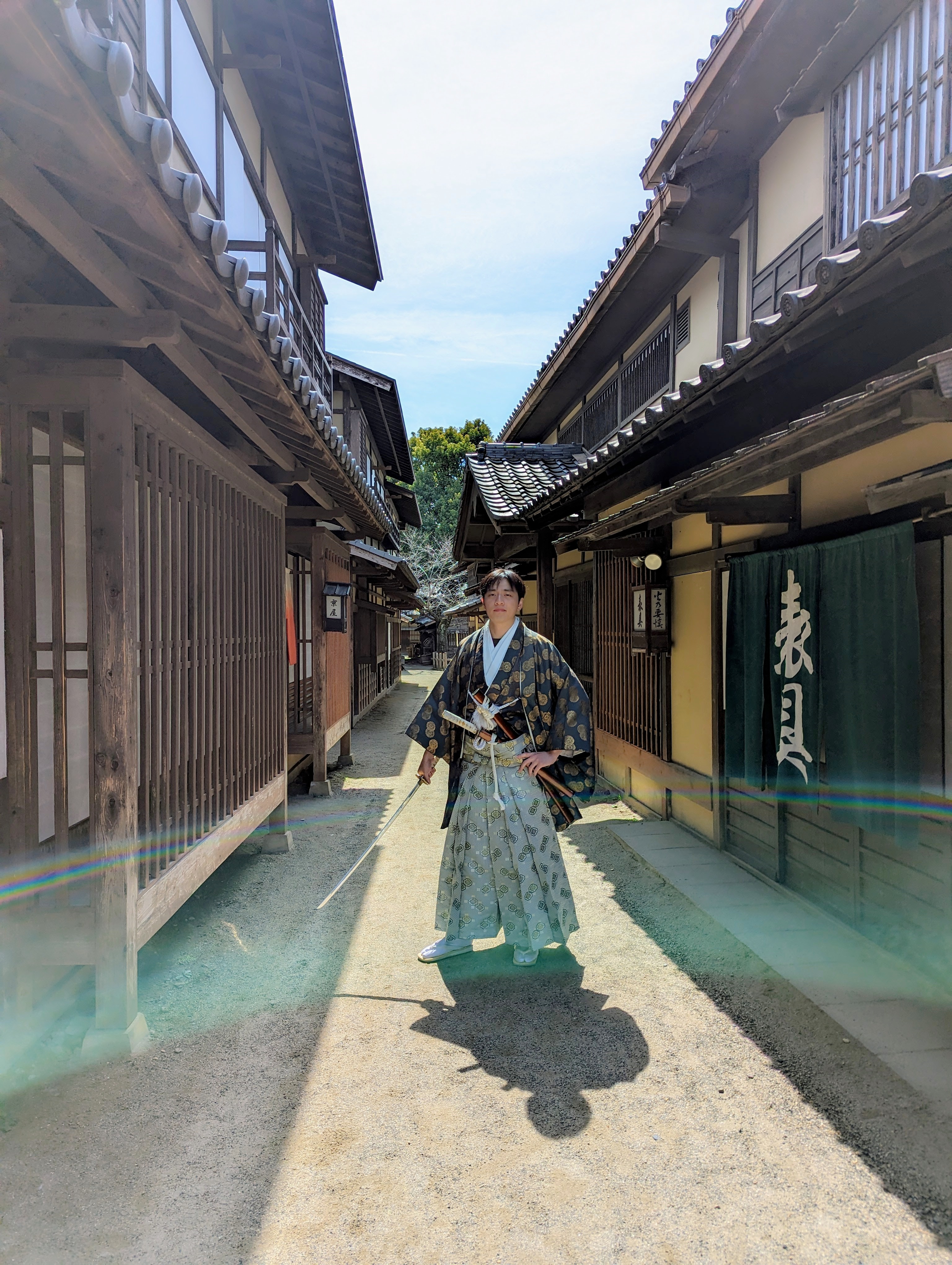 David posing in-between two buildings with a robe and sword in his hand.