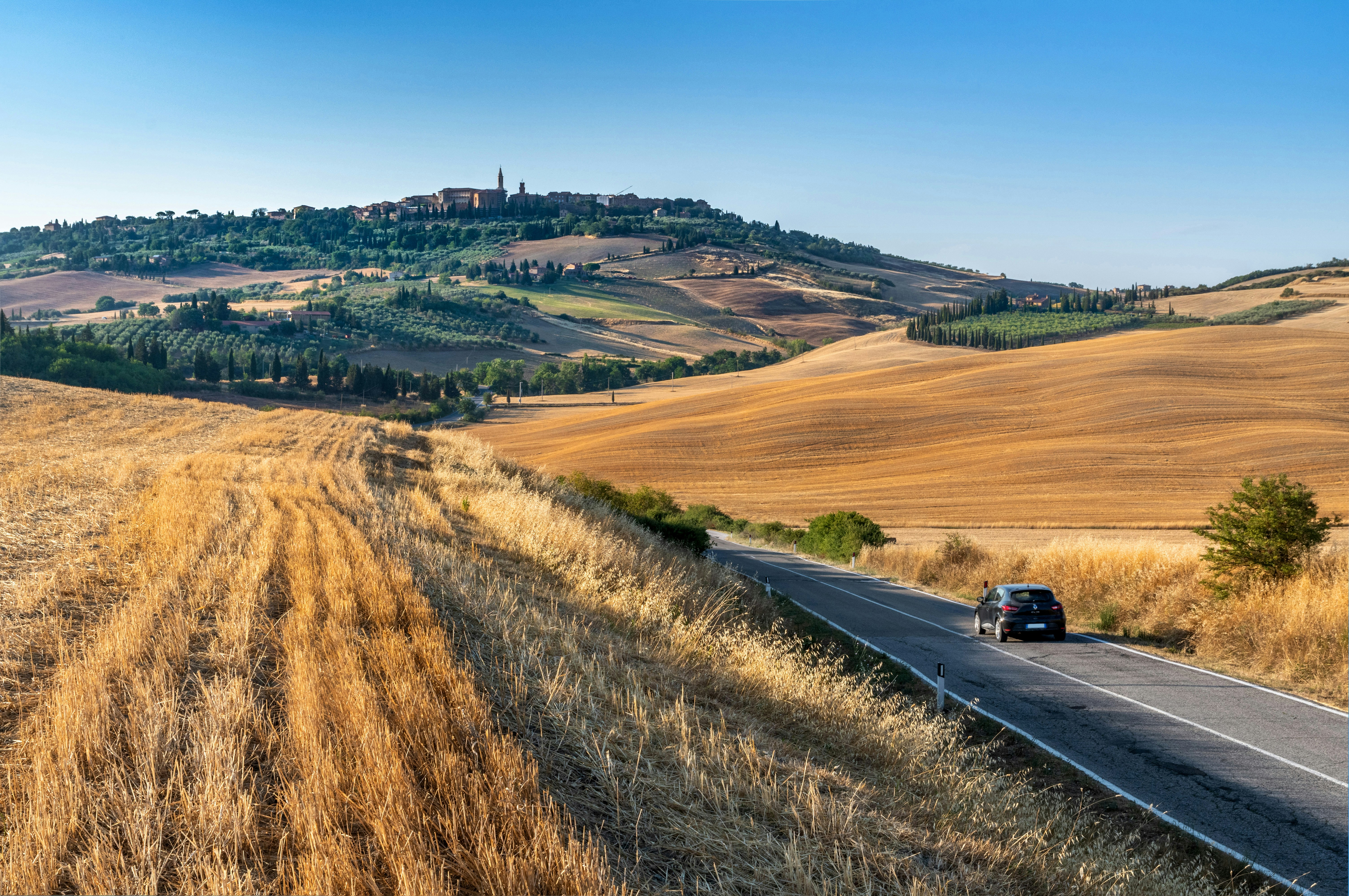 A picture of a black car on the road during the daytime.