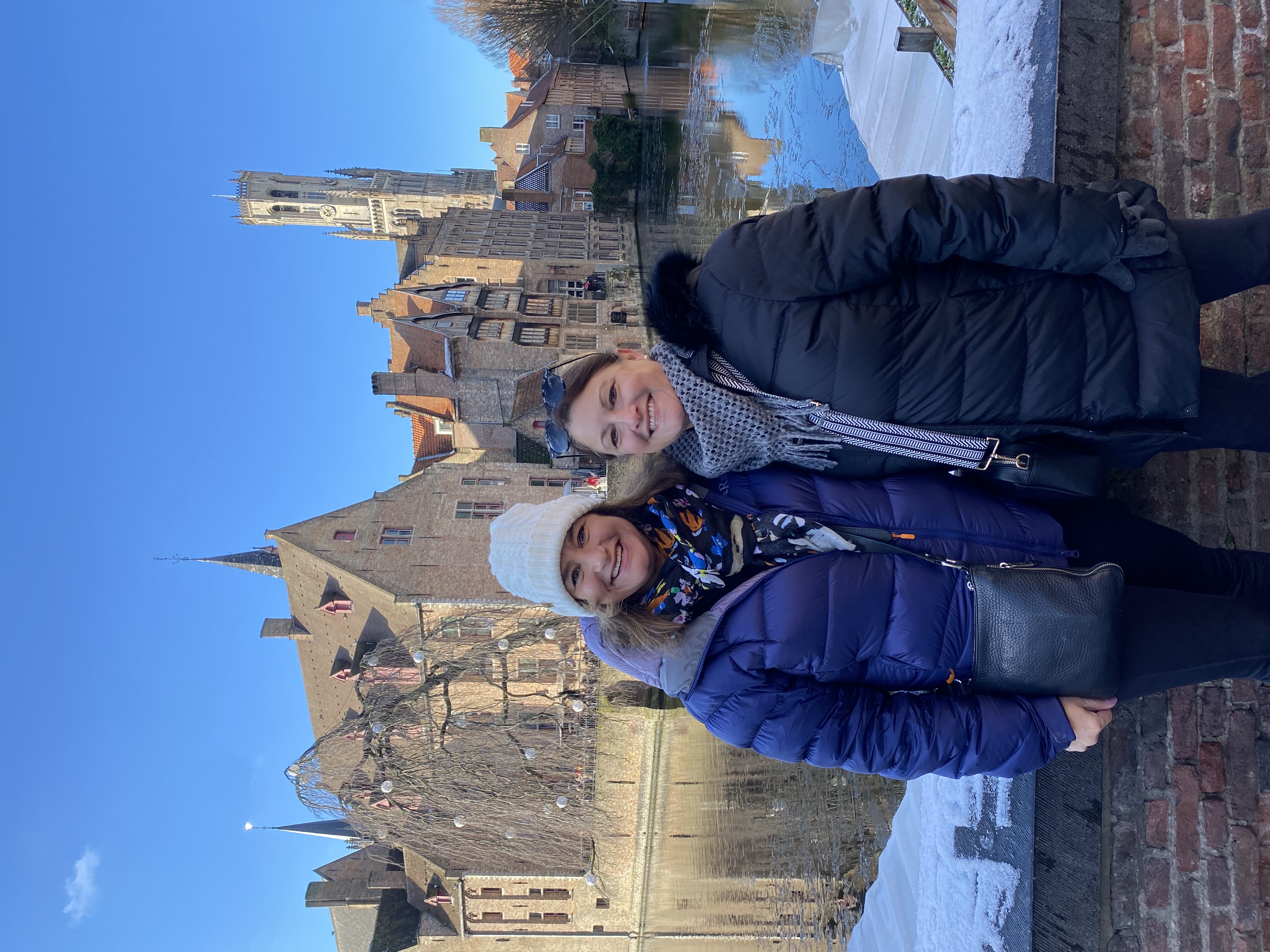 Travel advisor Leslie posing with a friend wearing a blue jacket and hat in front of a river