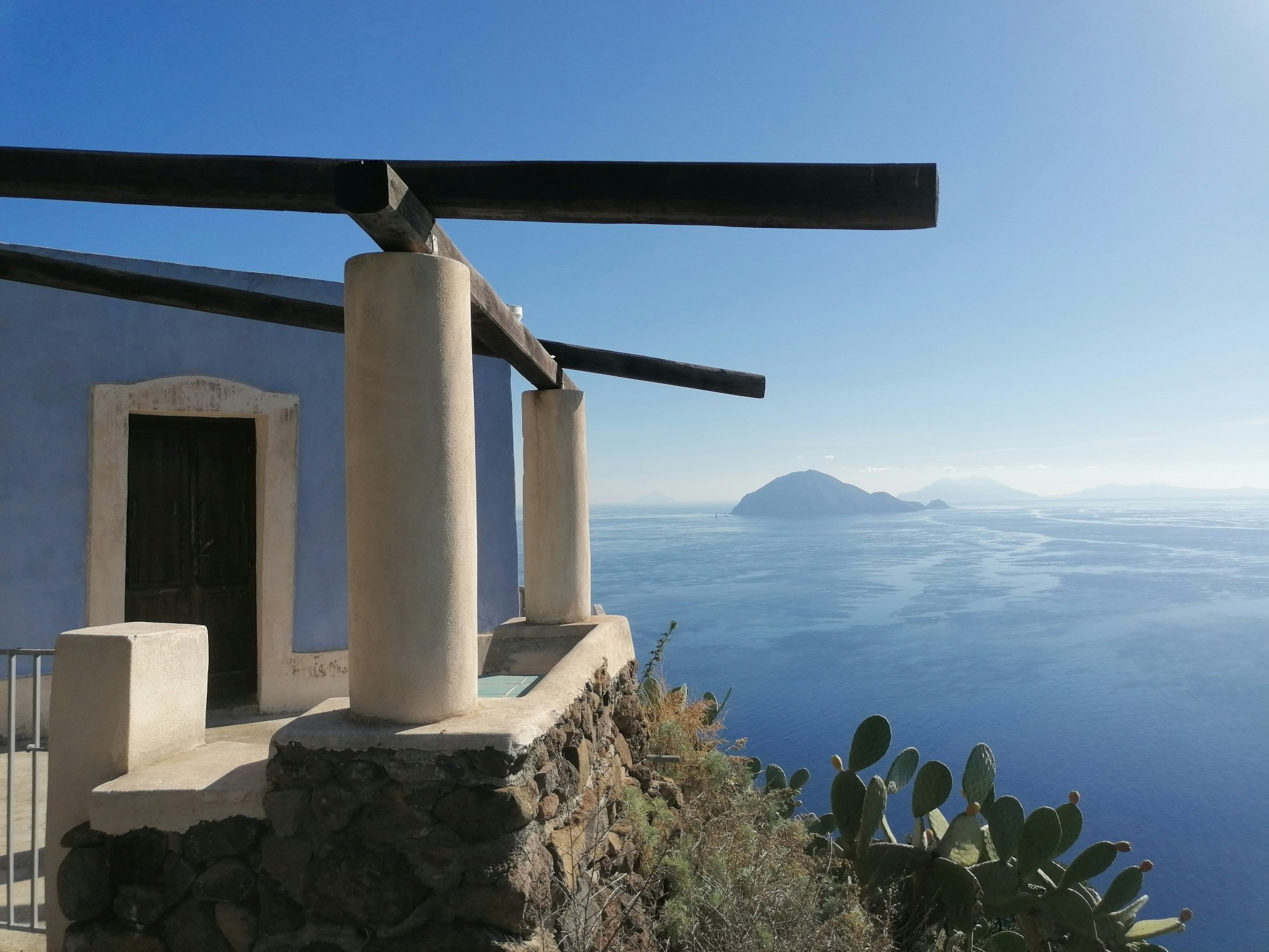 A stone structure with pillars and a body of water in the background.