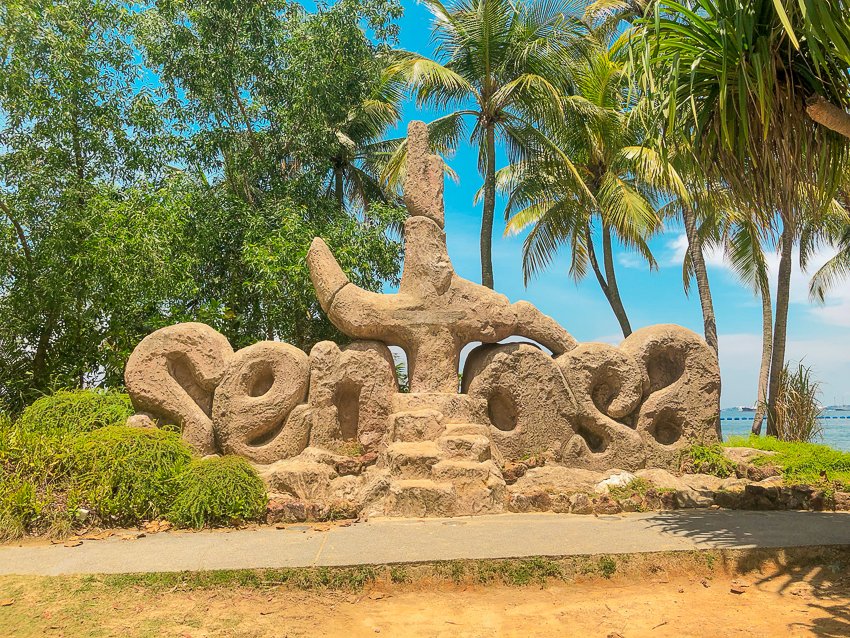 A light sign made out of sand on the beach surrounded by trees