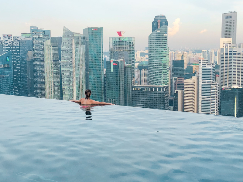 A person in an infinity pool overlooking a city skyline