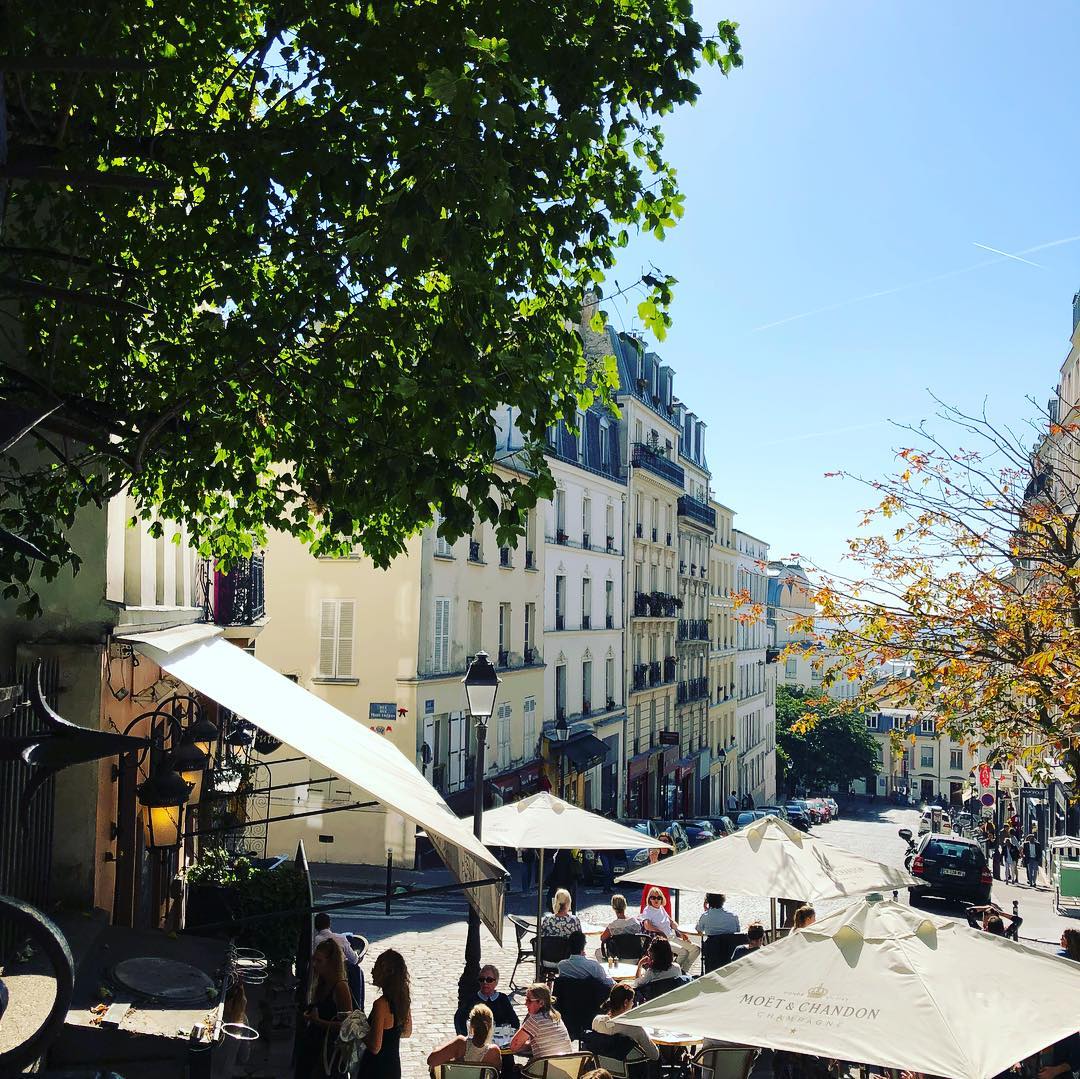 View of outdoor setup of a restaurant with umbrellas in a pretty street
