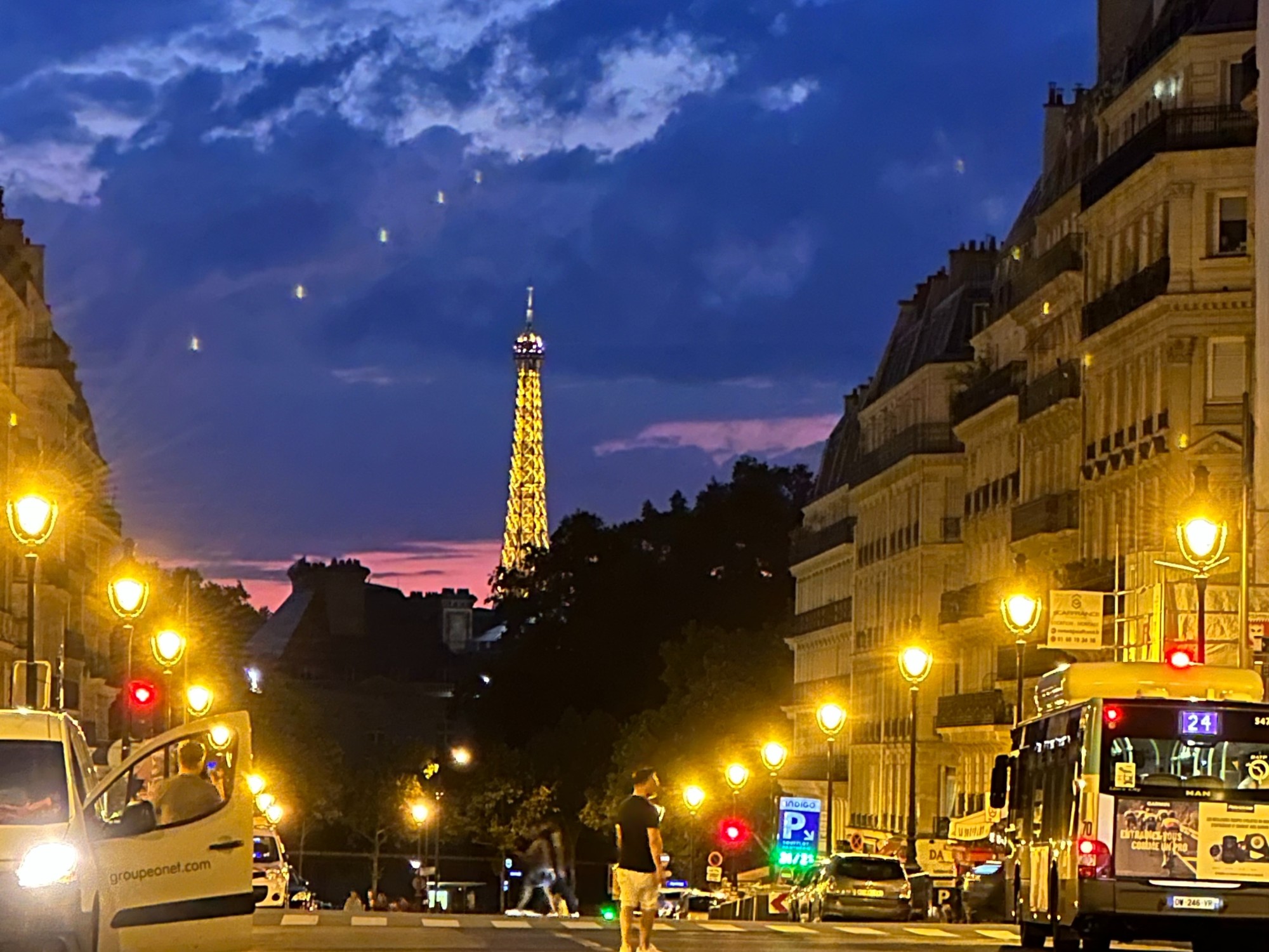 Street with view of well lit Eiffel tower at night.