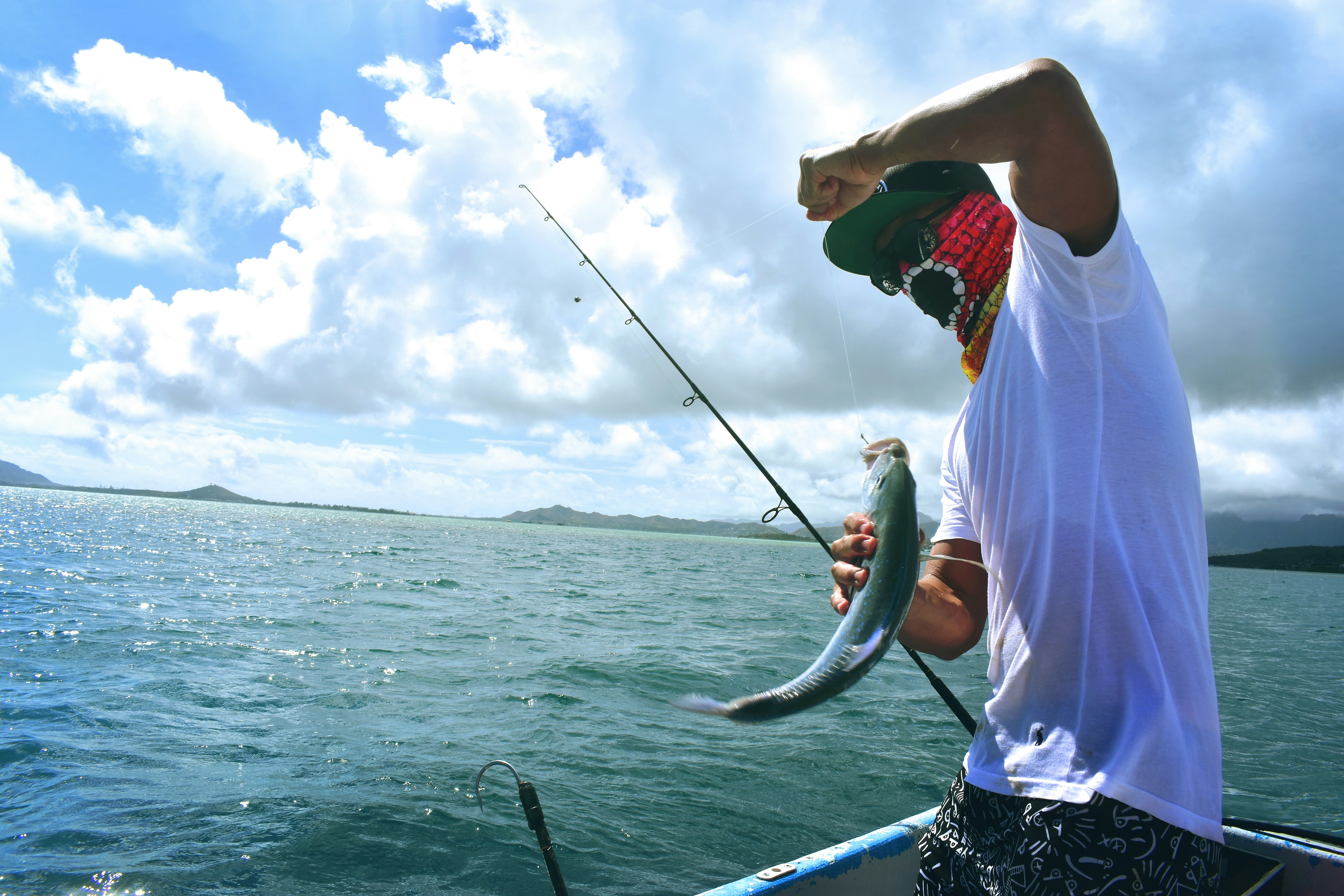 A picture of a man holding a fish on a boat during daytime.