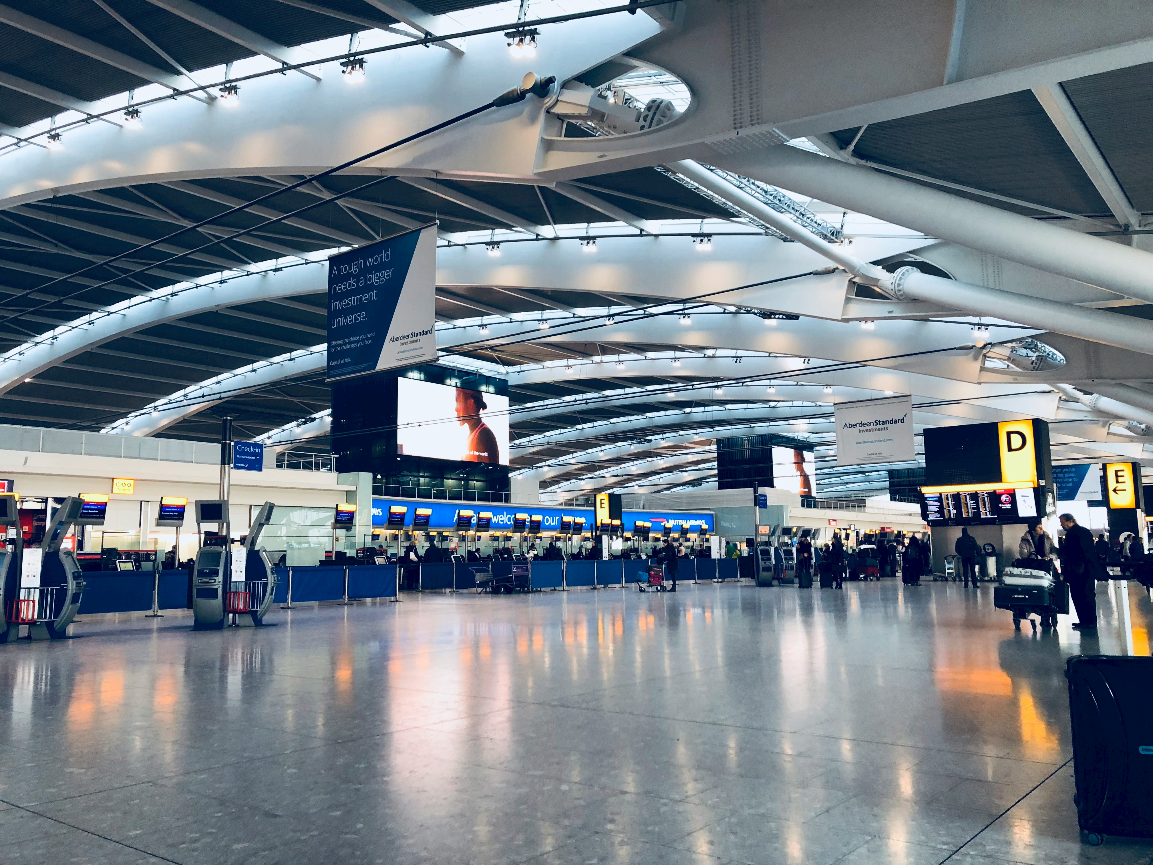A photo of an airport arrival area with people walking around.