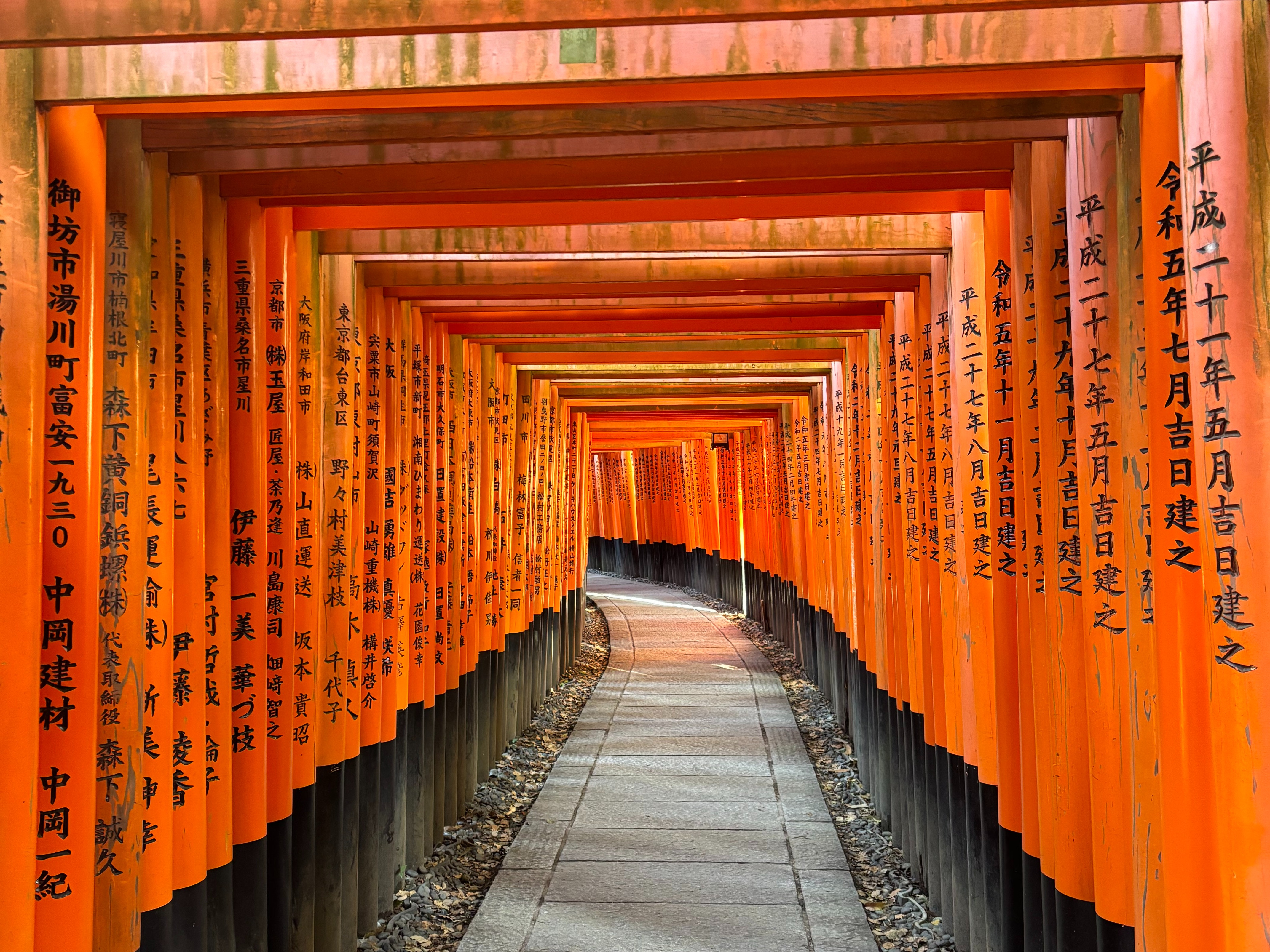 Fushumi Shrine with red pillars on either side of a concrete path with Japanese characters.
