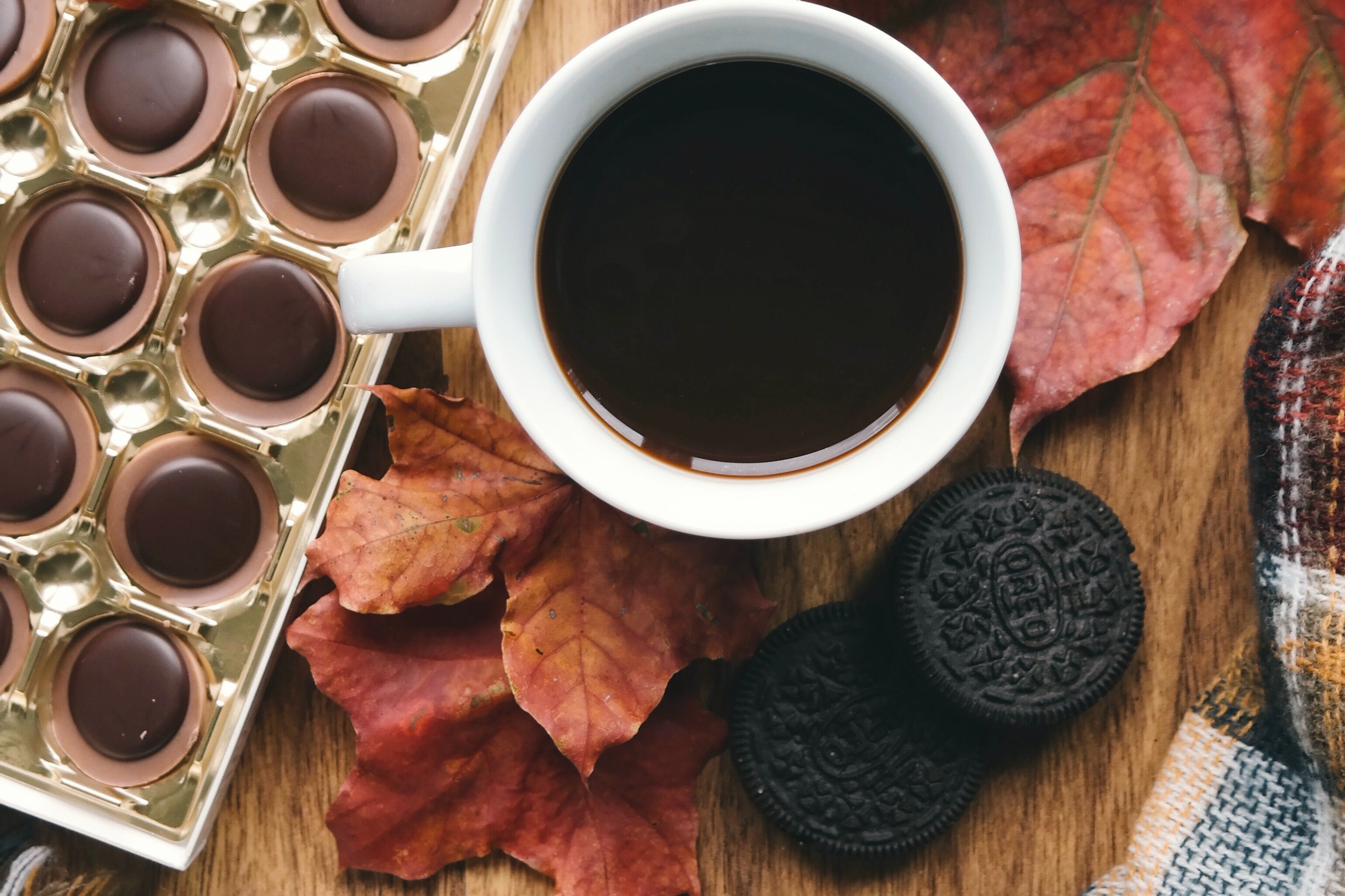 White ceramic cup with coffee and sweet treat scattered around the table.