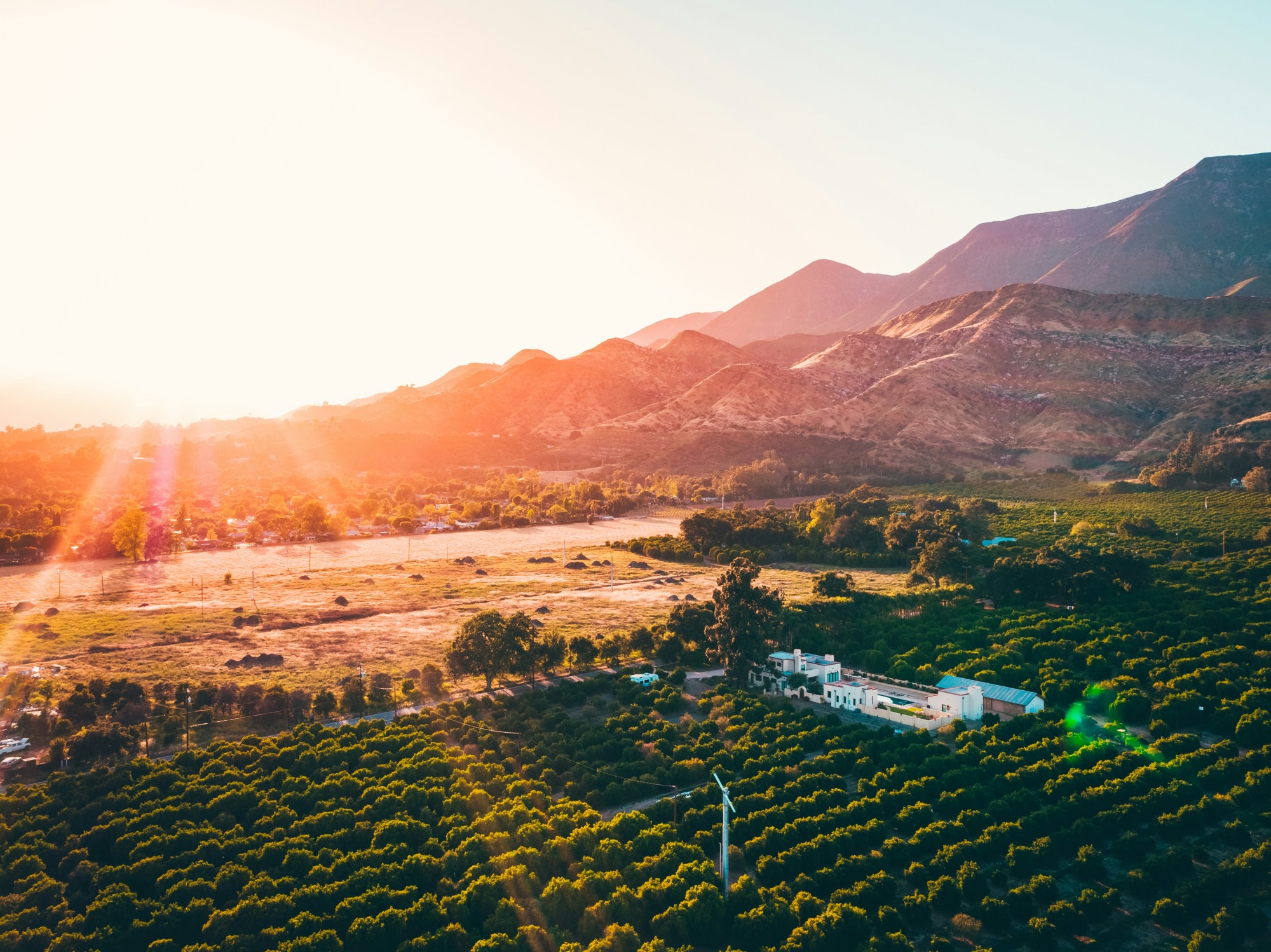 A beaming sunset over a farm and mountain range in Ojai.