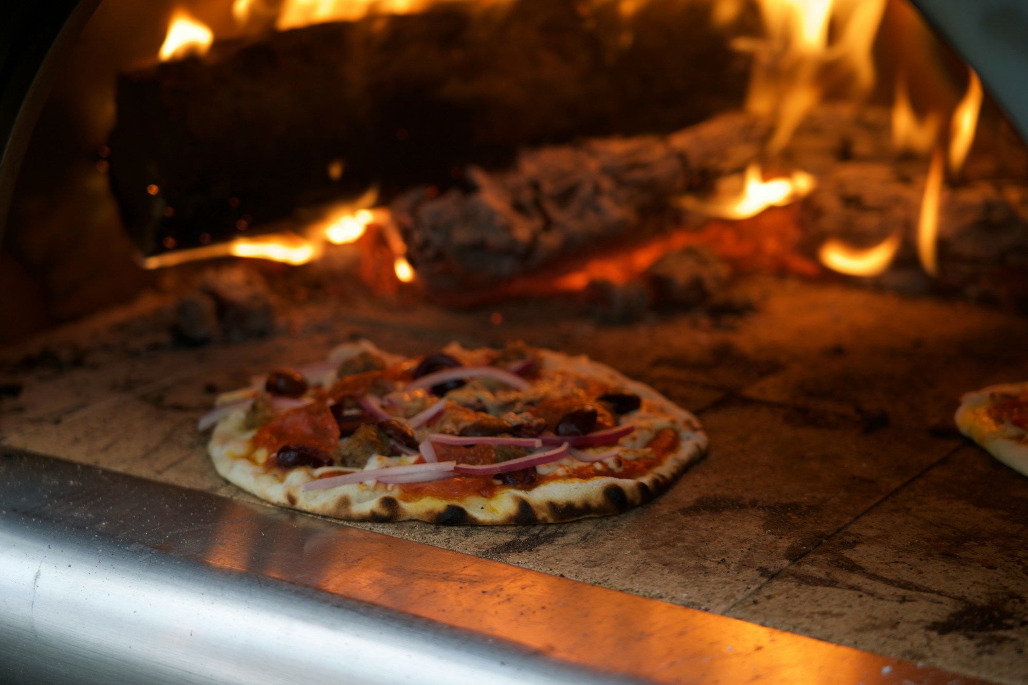 Pizza inside oven with fired bricks.