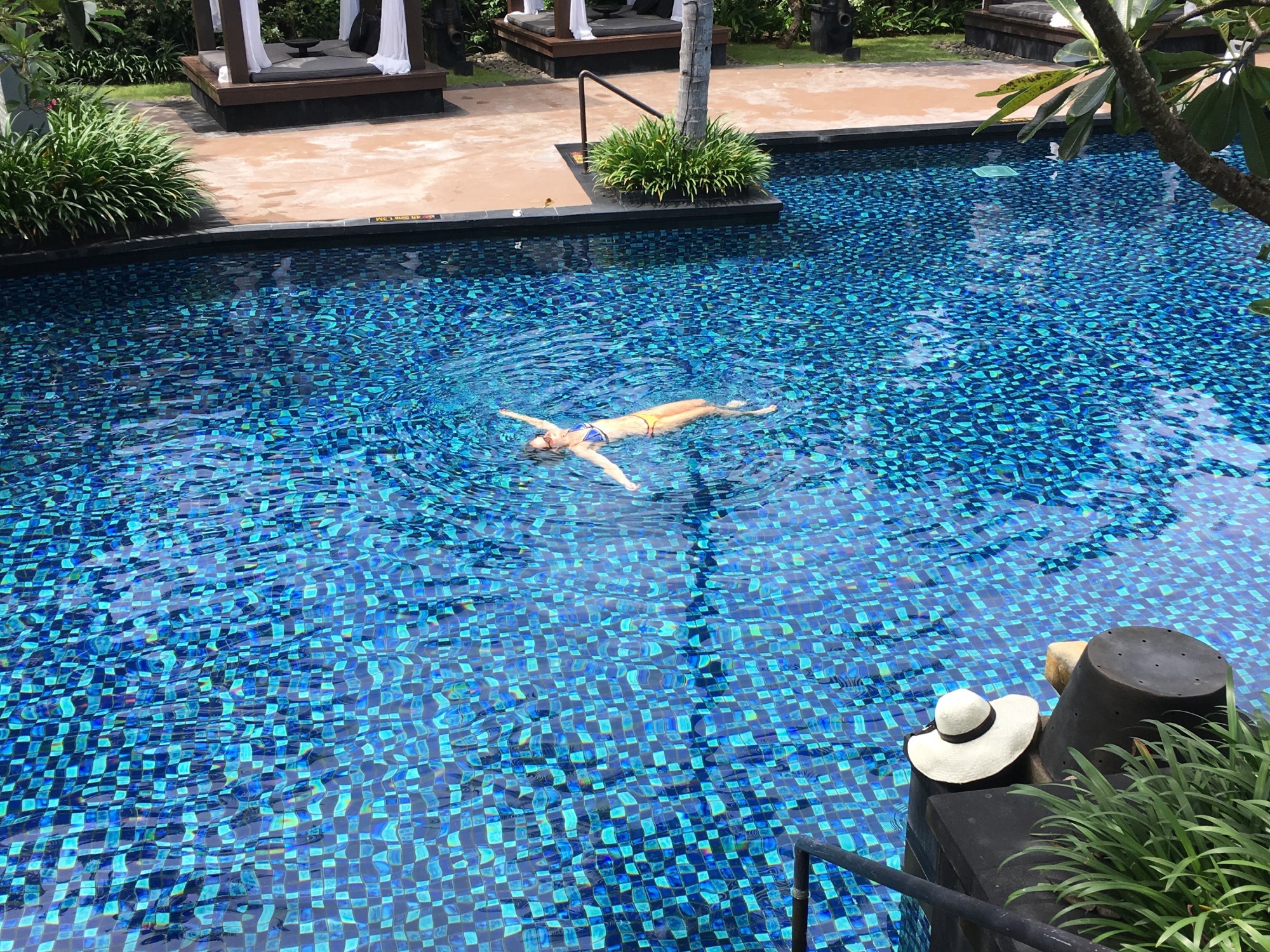 A woman floating in a pool at a resort.
