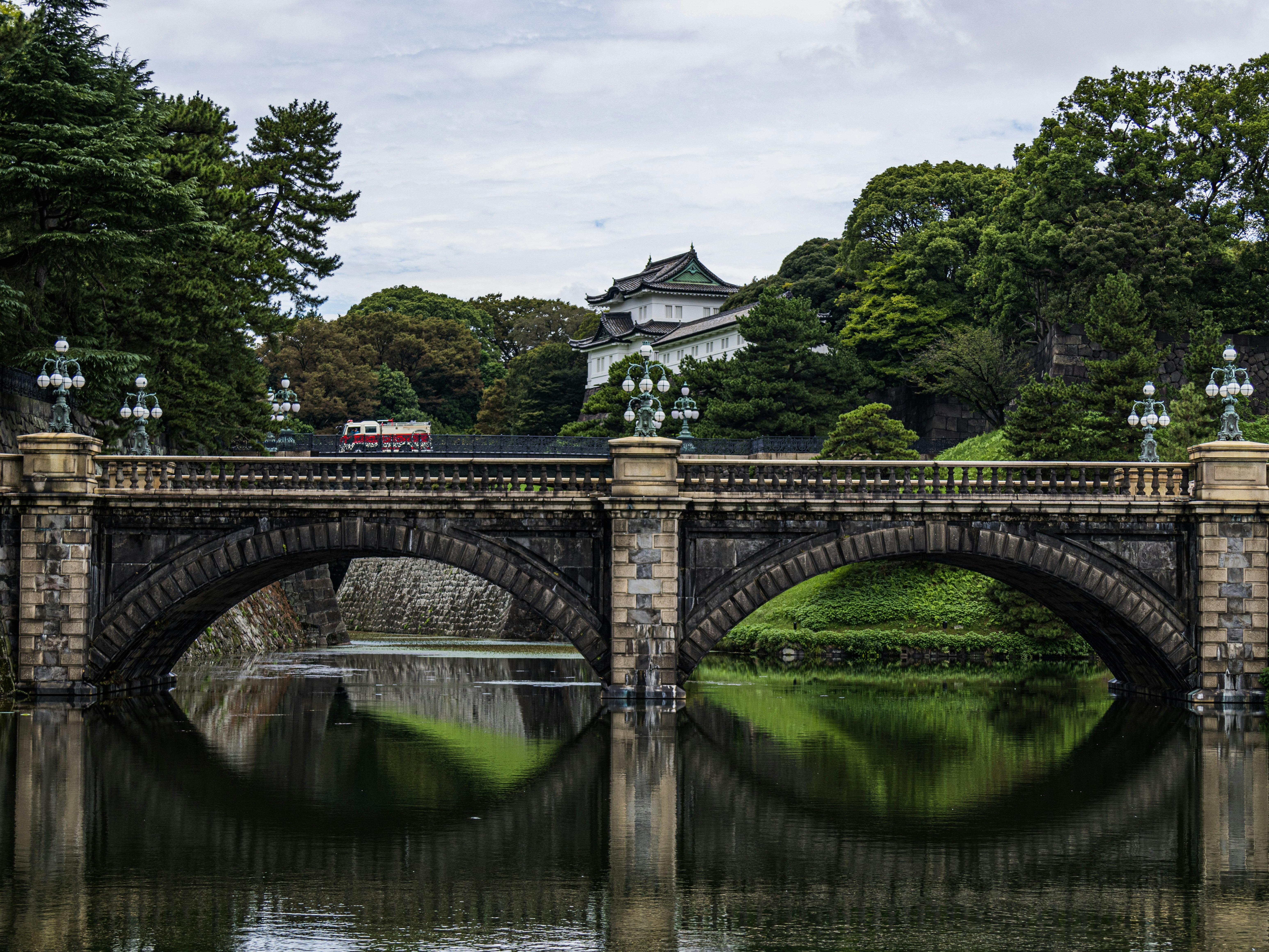 A picture of a beautiful stone bridge over a body of water with a building in the background.