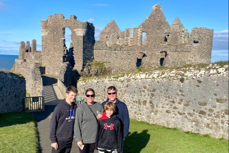 A family posing in front of castle ruins during the daytime