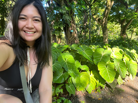 Advisor posing for a photo in front of a bush of plants