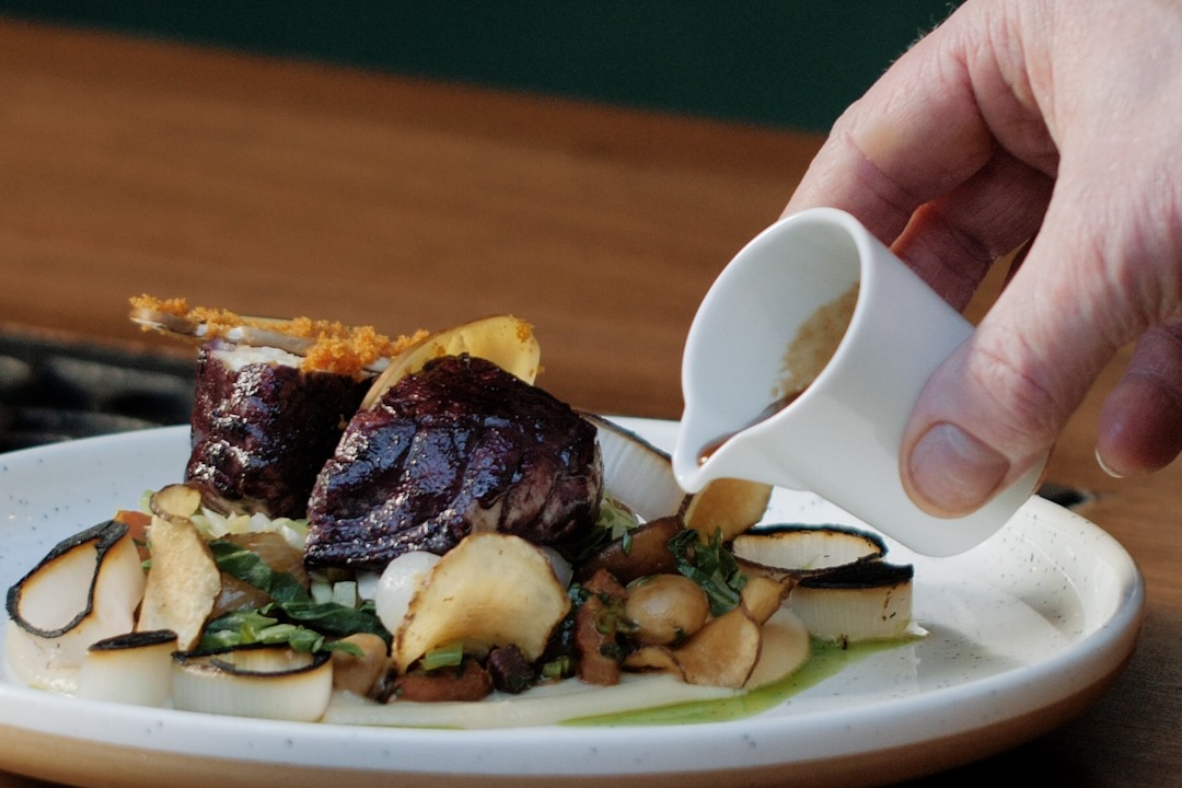 A plate of food with a person pouring gravy onto it.