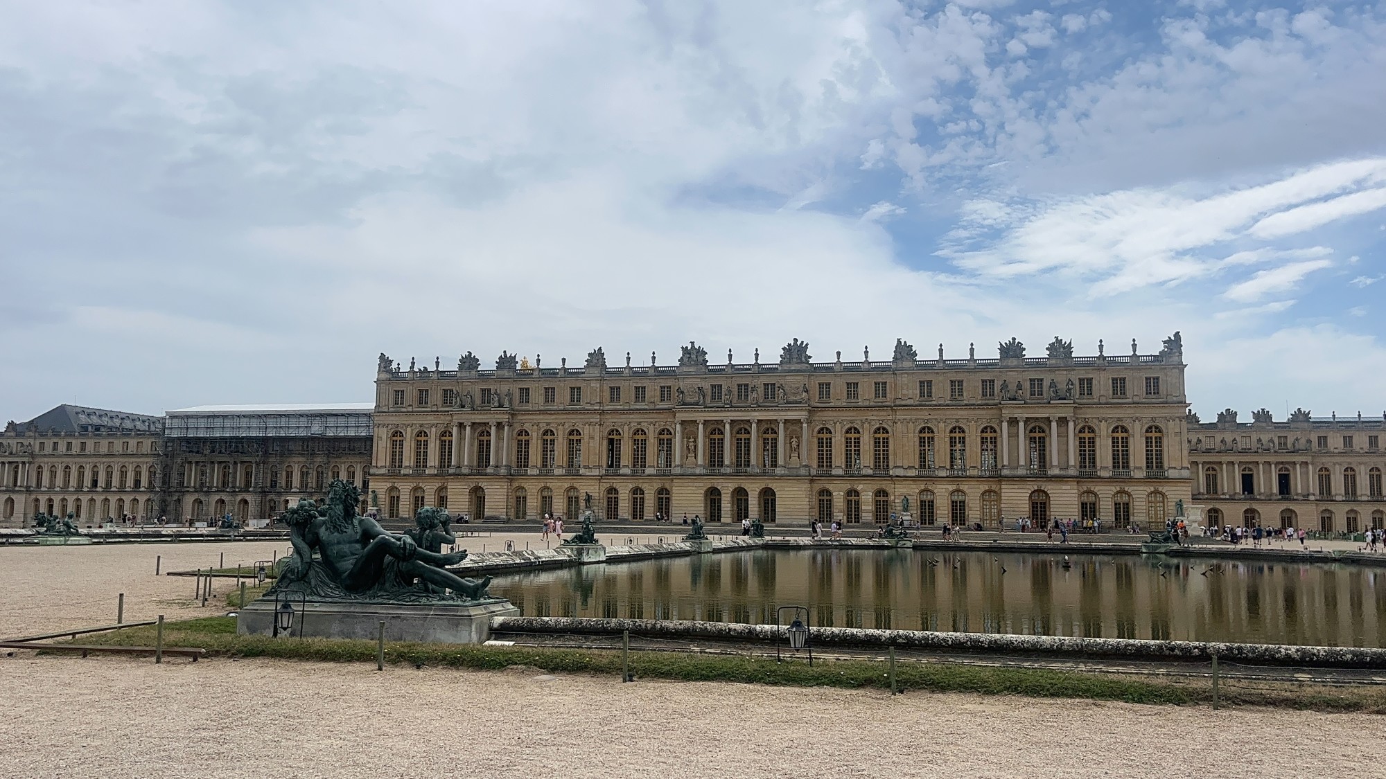 A palace with pool and statues in front.
