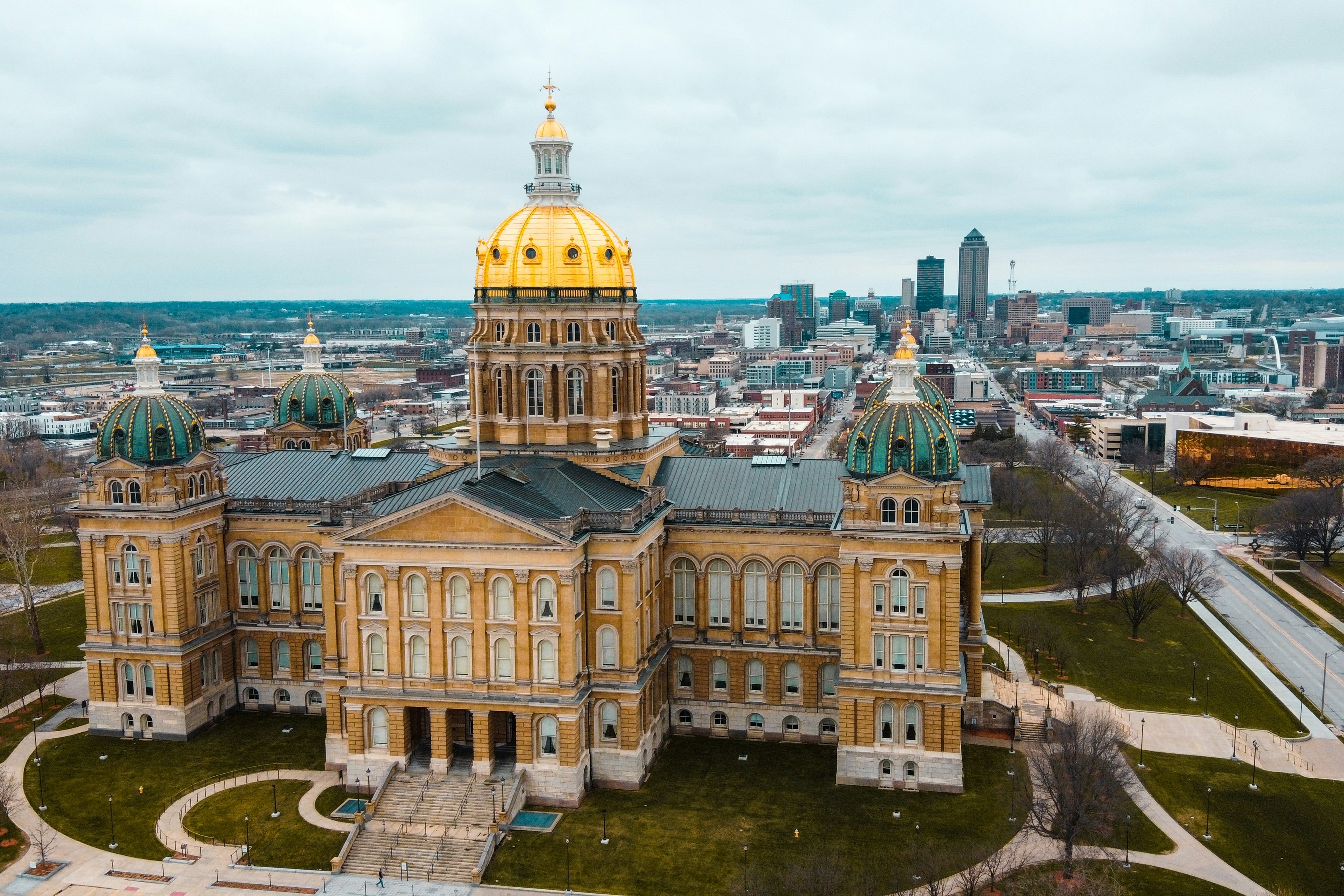 an aerial view of the capitol building with a golden dome at its center.