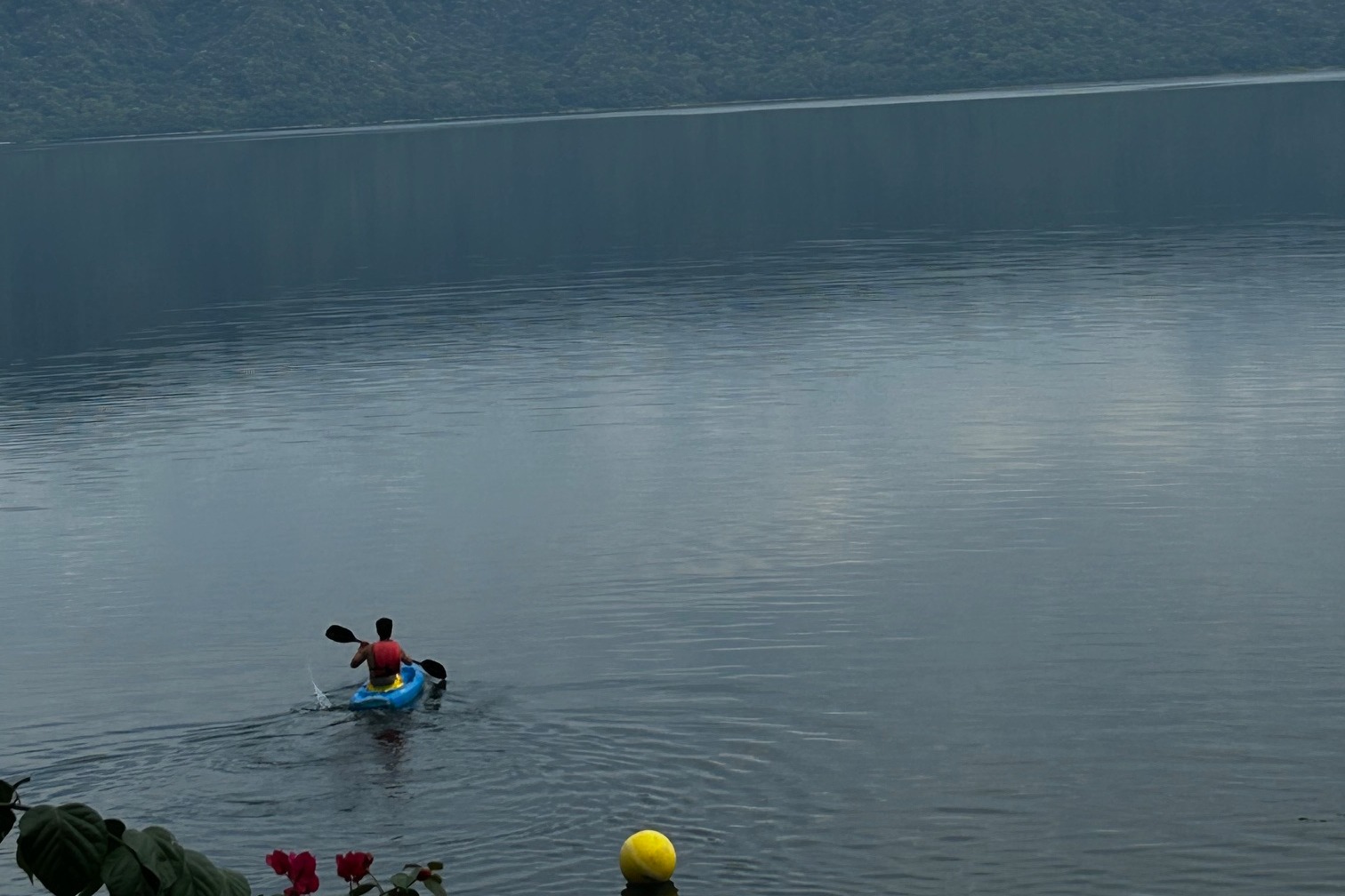 A picture of a person on a blue kayak over a large body of water.