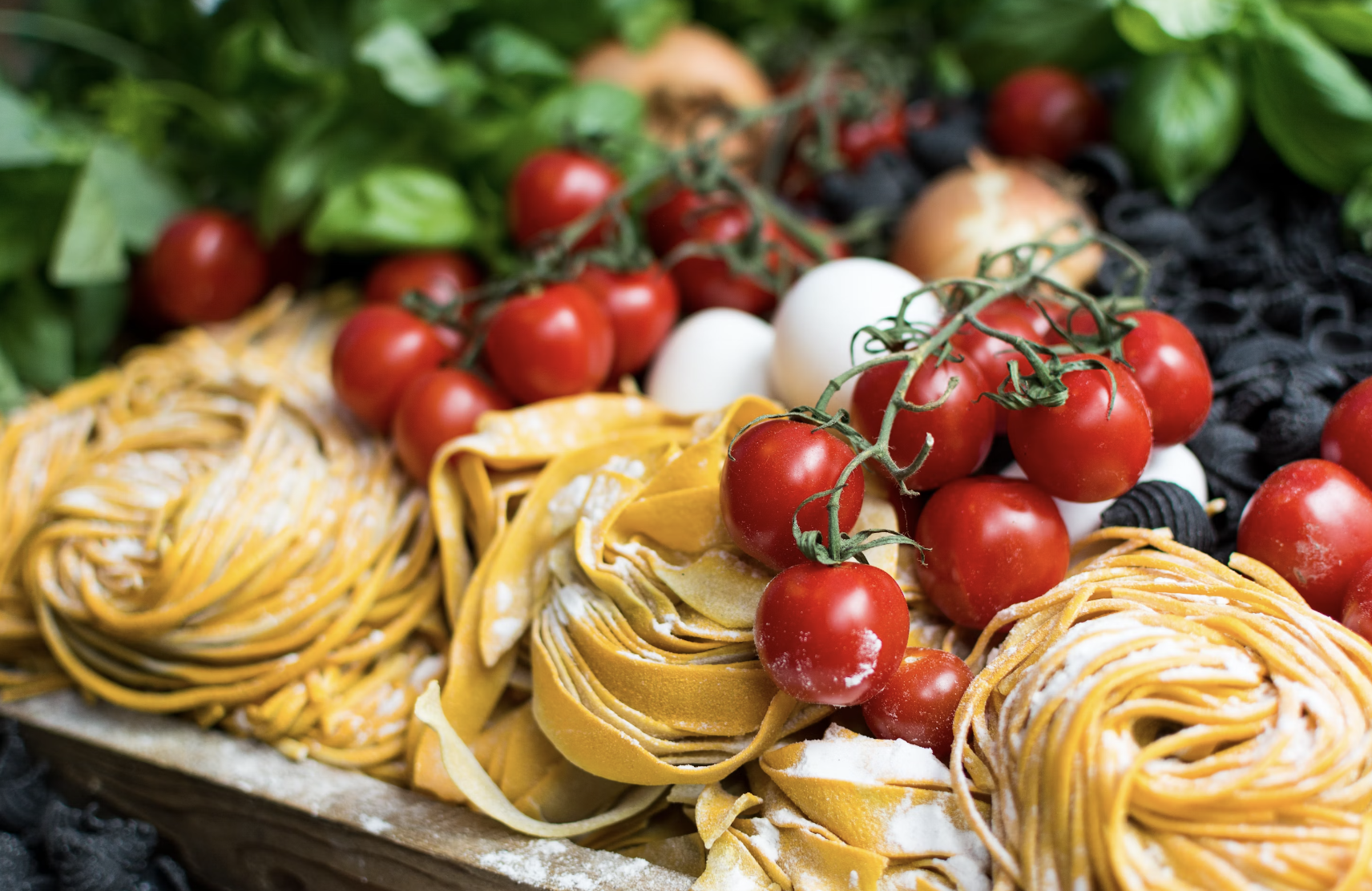 A view of dried noodles, tomatoes and other dry ingredients on a table.