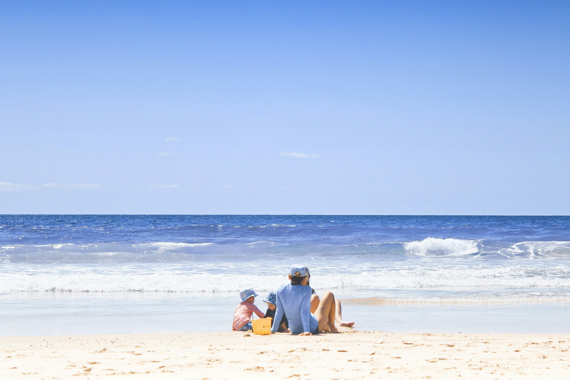 A family with baby sitting on a beach.