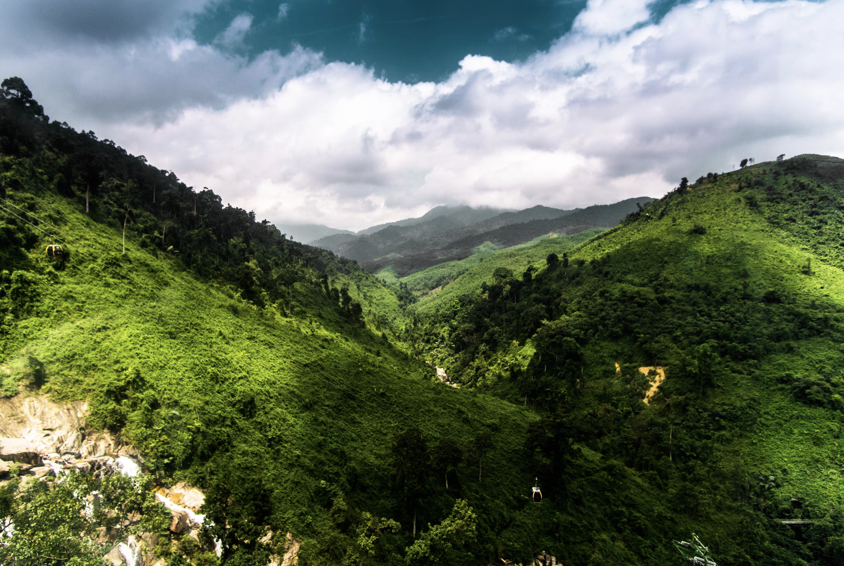 An aerial view of lush and green mountain ranges under the thick clouds.