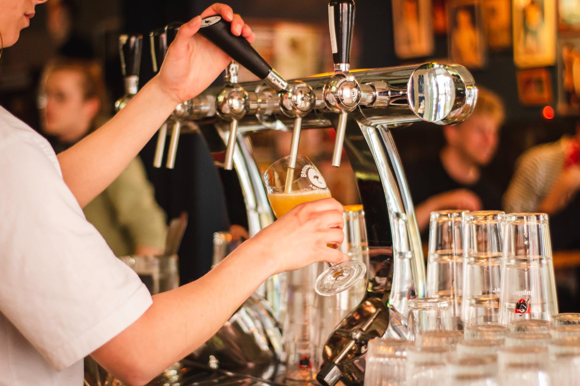 A person pouring a beer from a tap