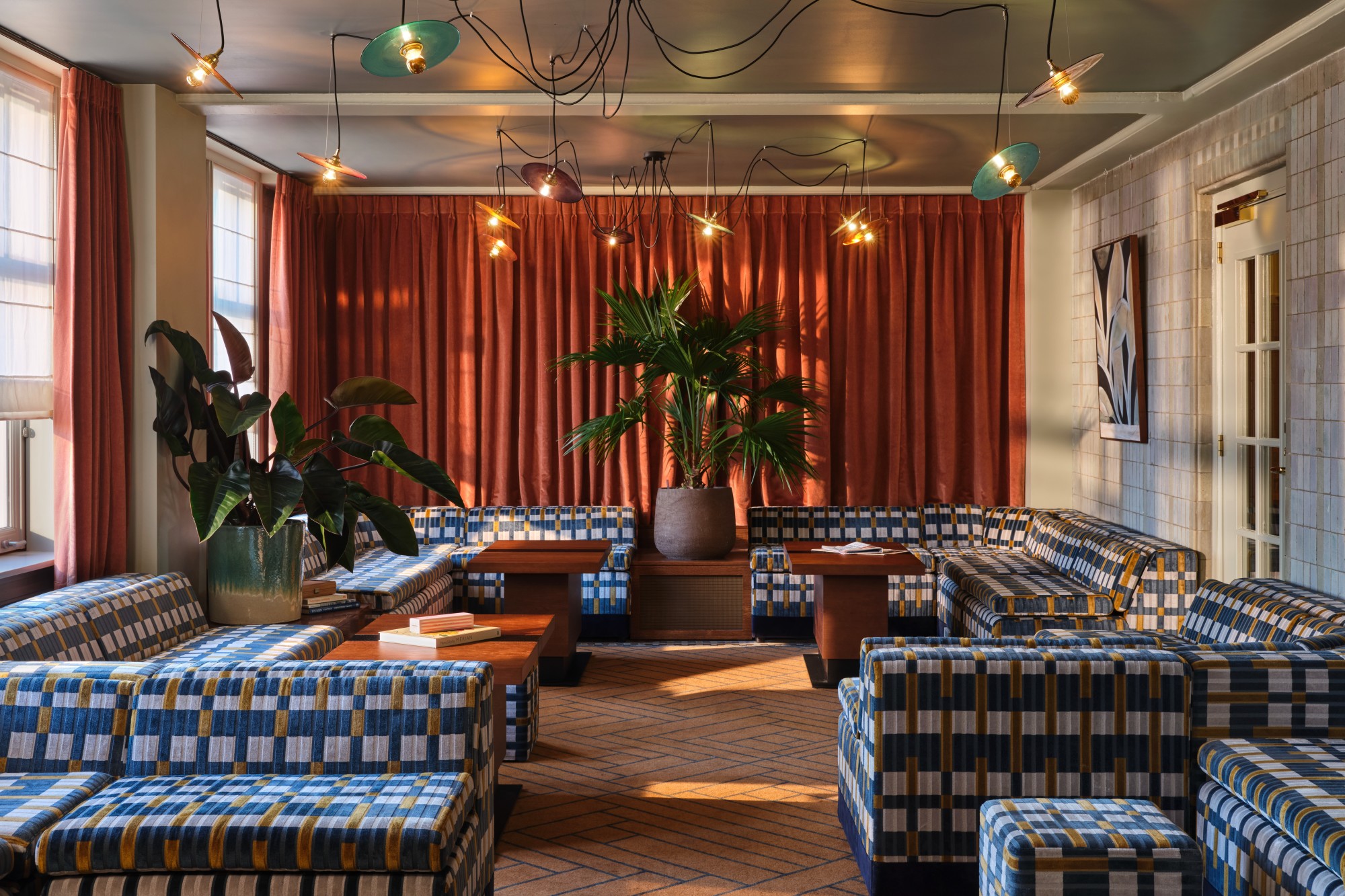 blue-and-white couches in a lounge with orange curtains and leafy plants