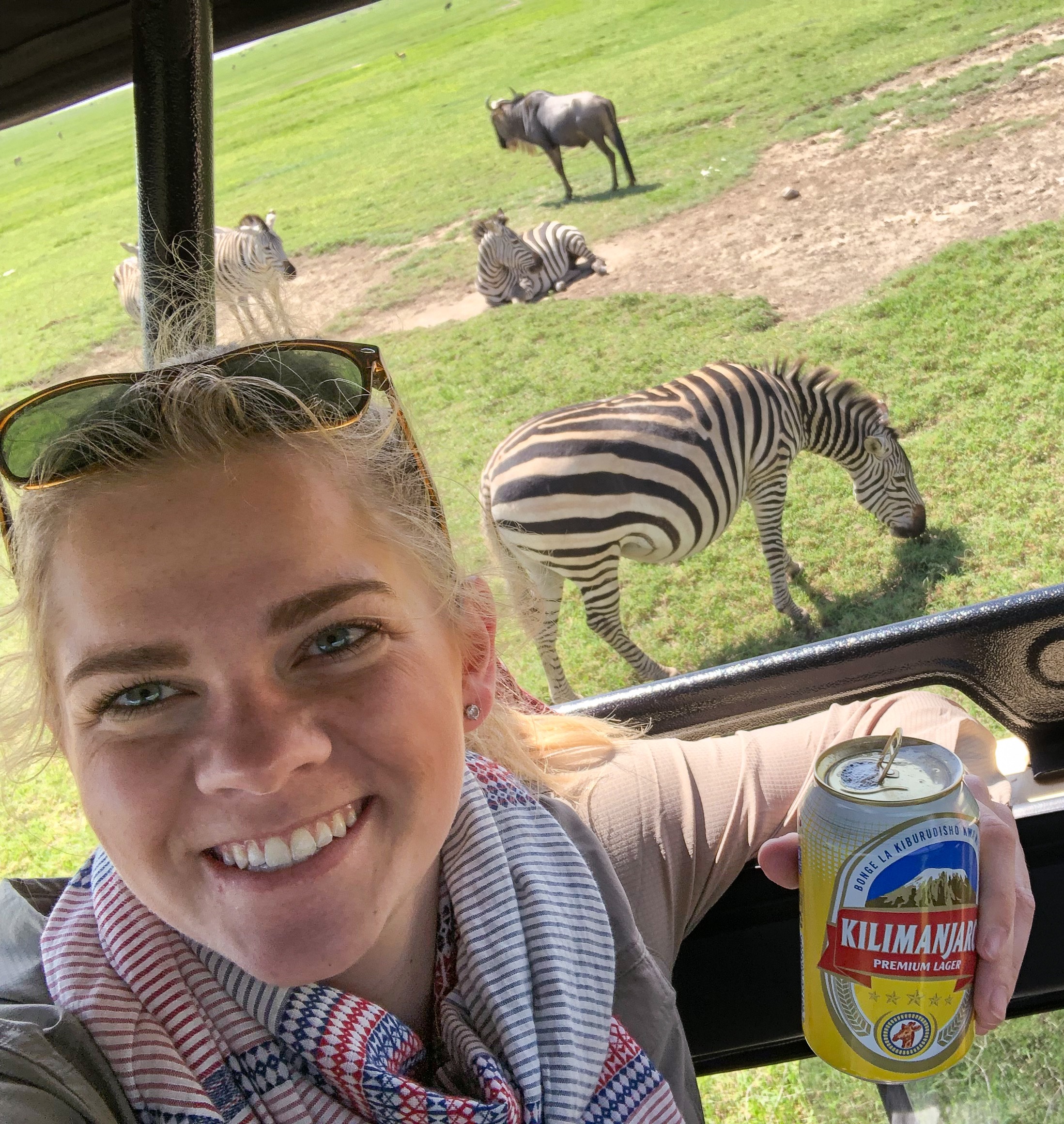 Picture of Adrianna in jeep on a safari with wild zebras in the distance