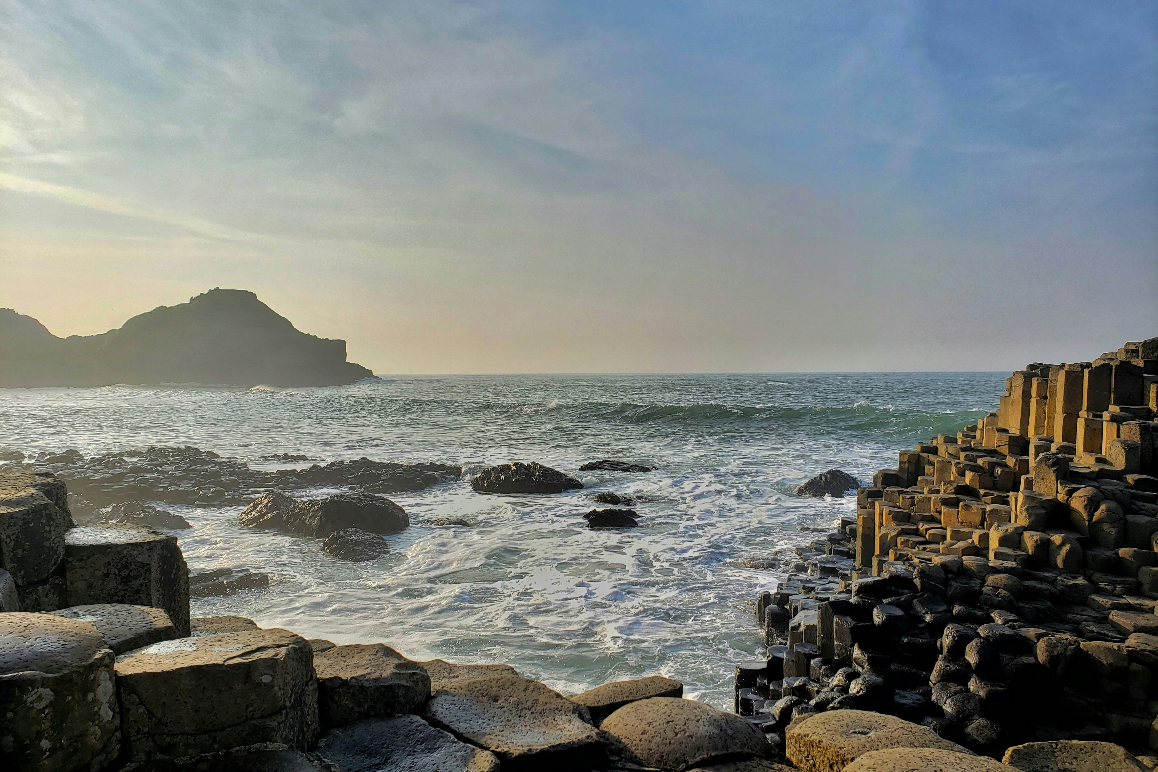 A picture of brown rocks near seashore during the daytime.
