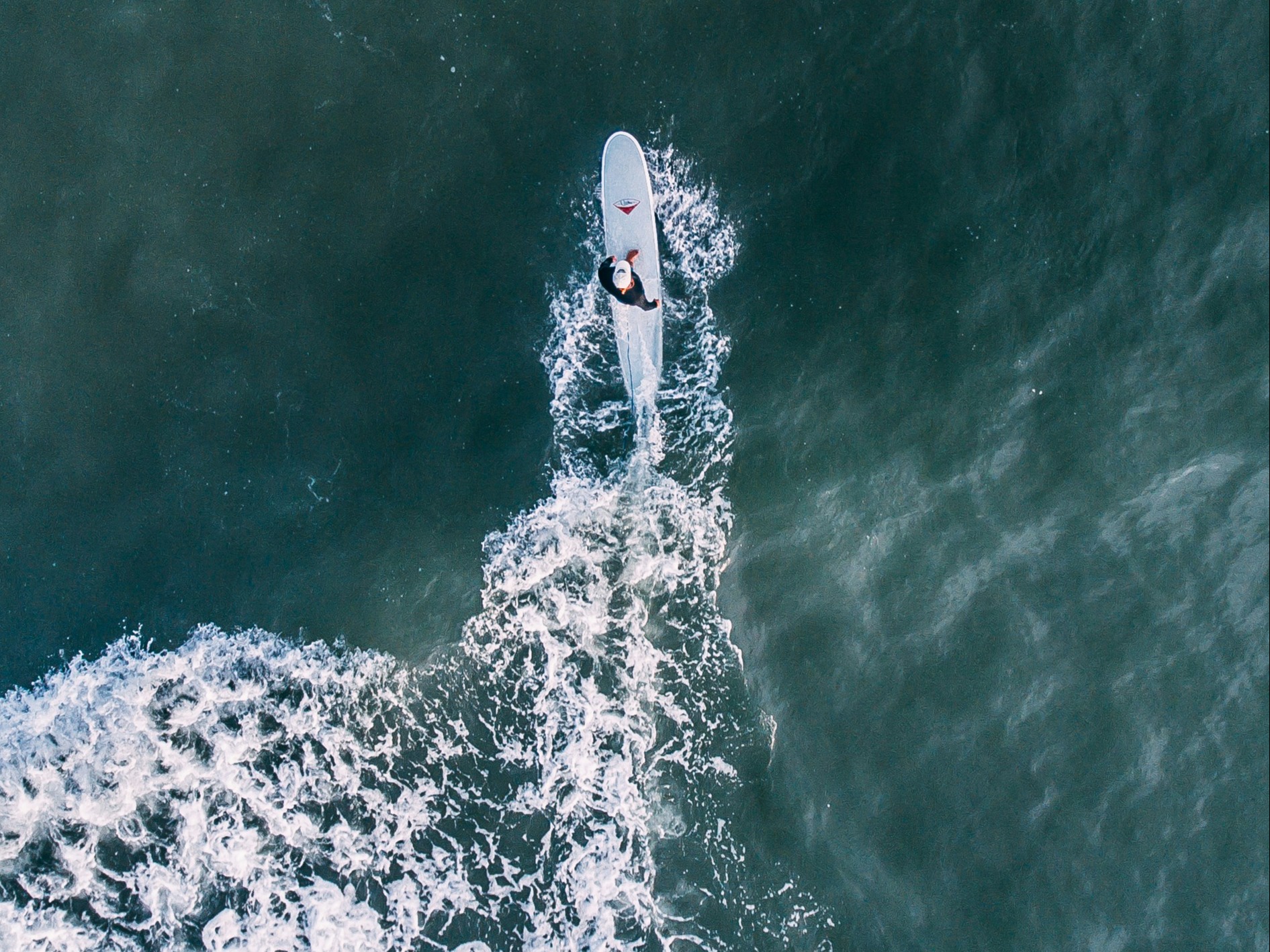 An aerial view of a person surfing on water during daytime.