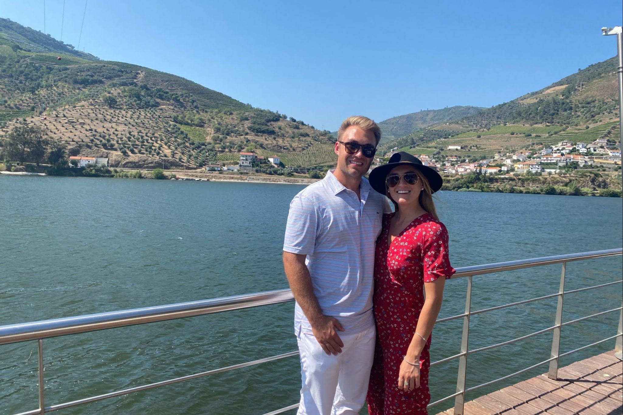 A couple posing near the waterfront at a restaurant during the daytime.