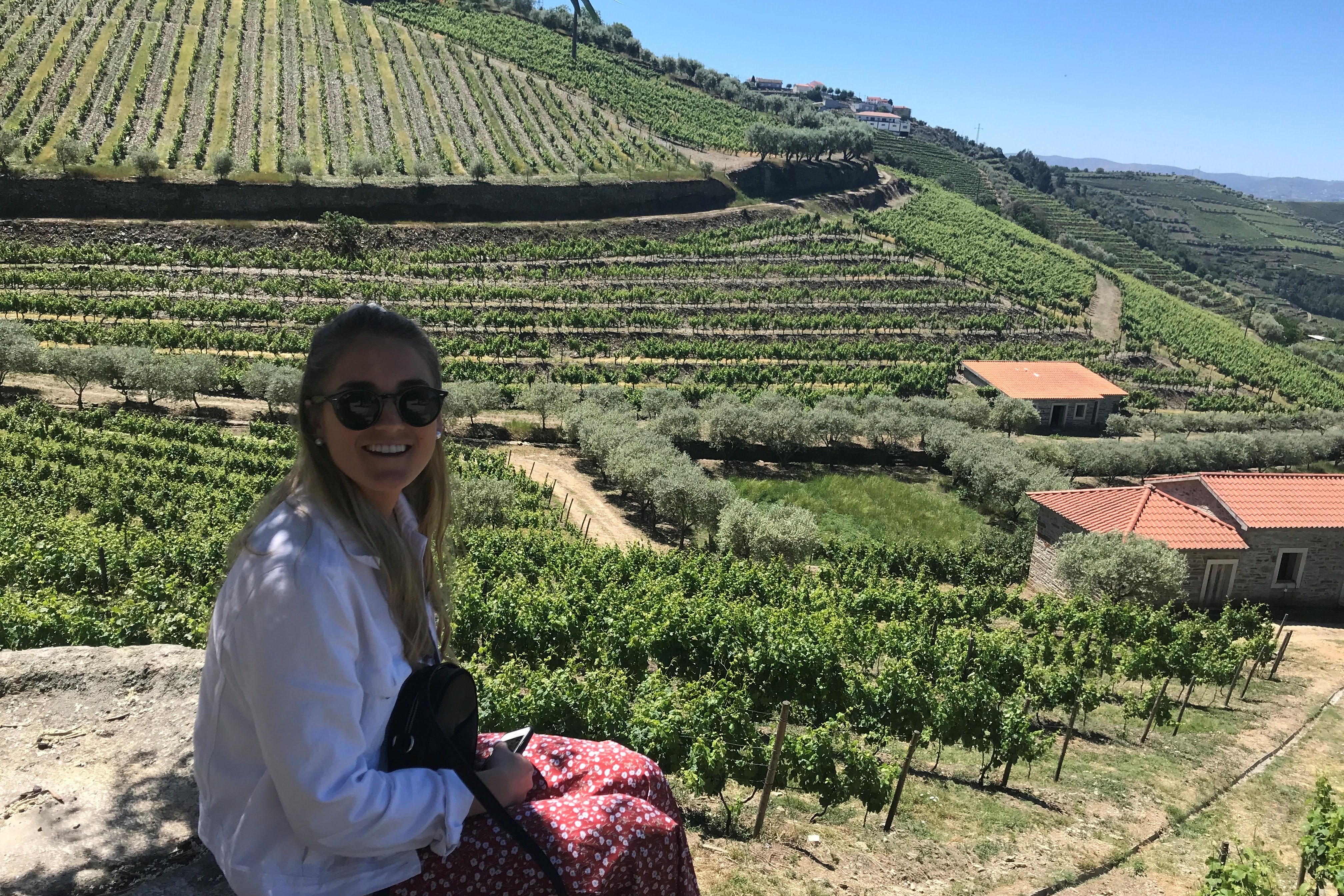 A picture of Tori in a white shirt sitting near the Douro Valley winery.