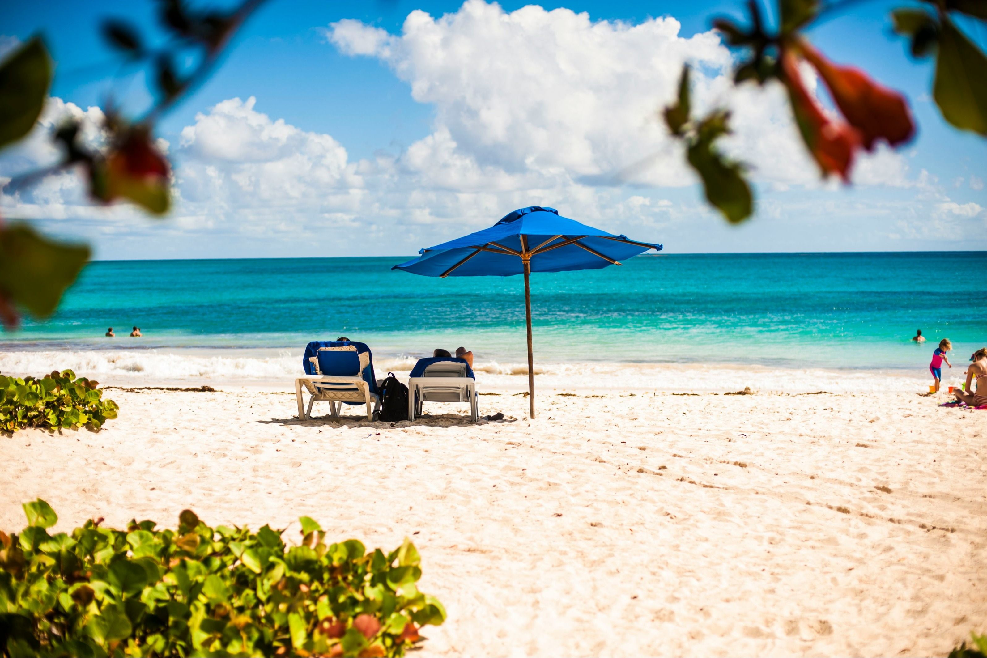 A far view of a couple laying on beach bed during daytime.