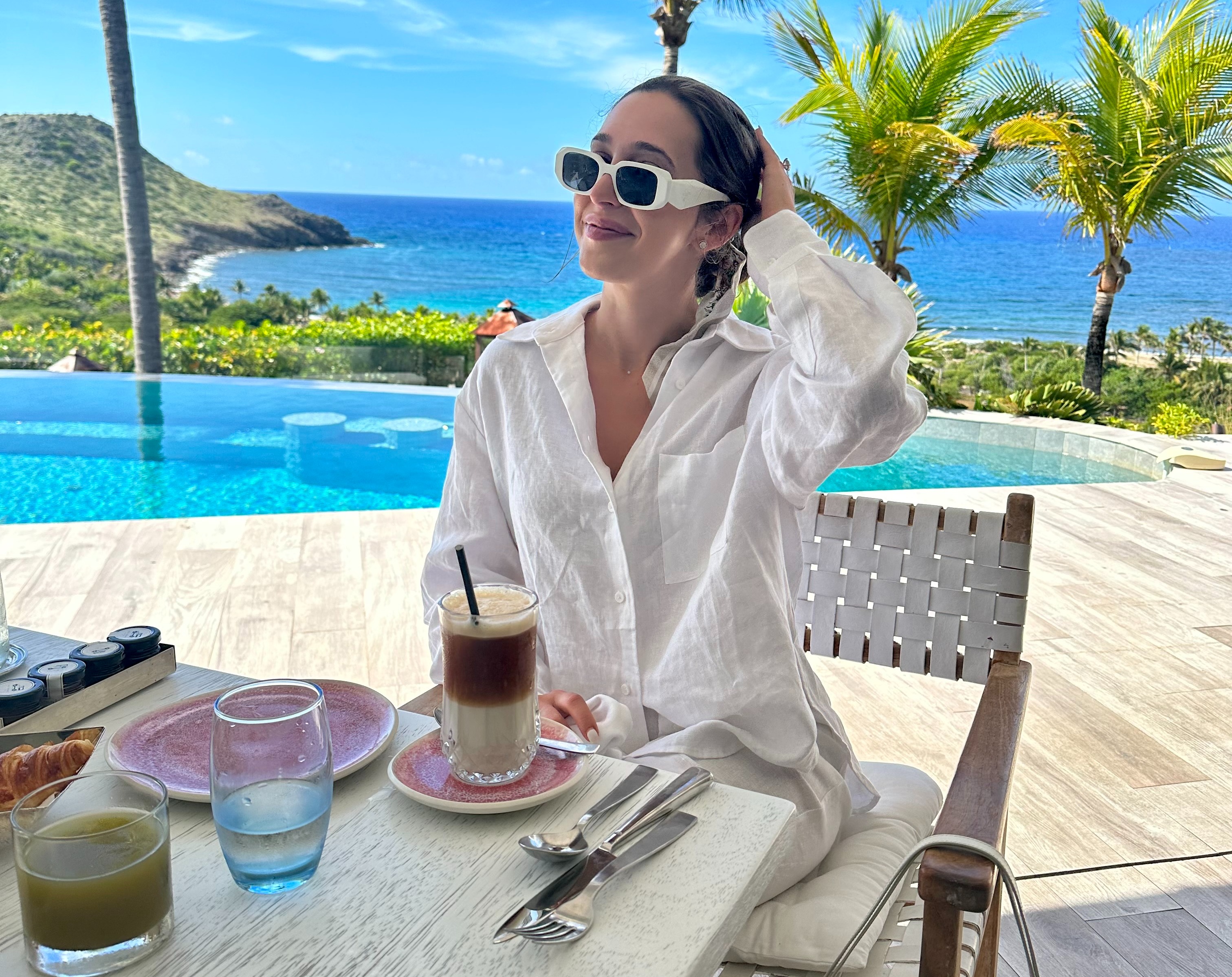 A woman with white clothes dining near the beach during the daytime.