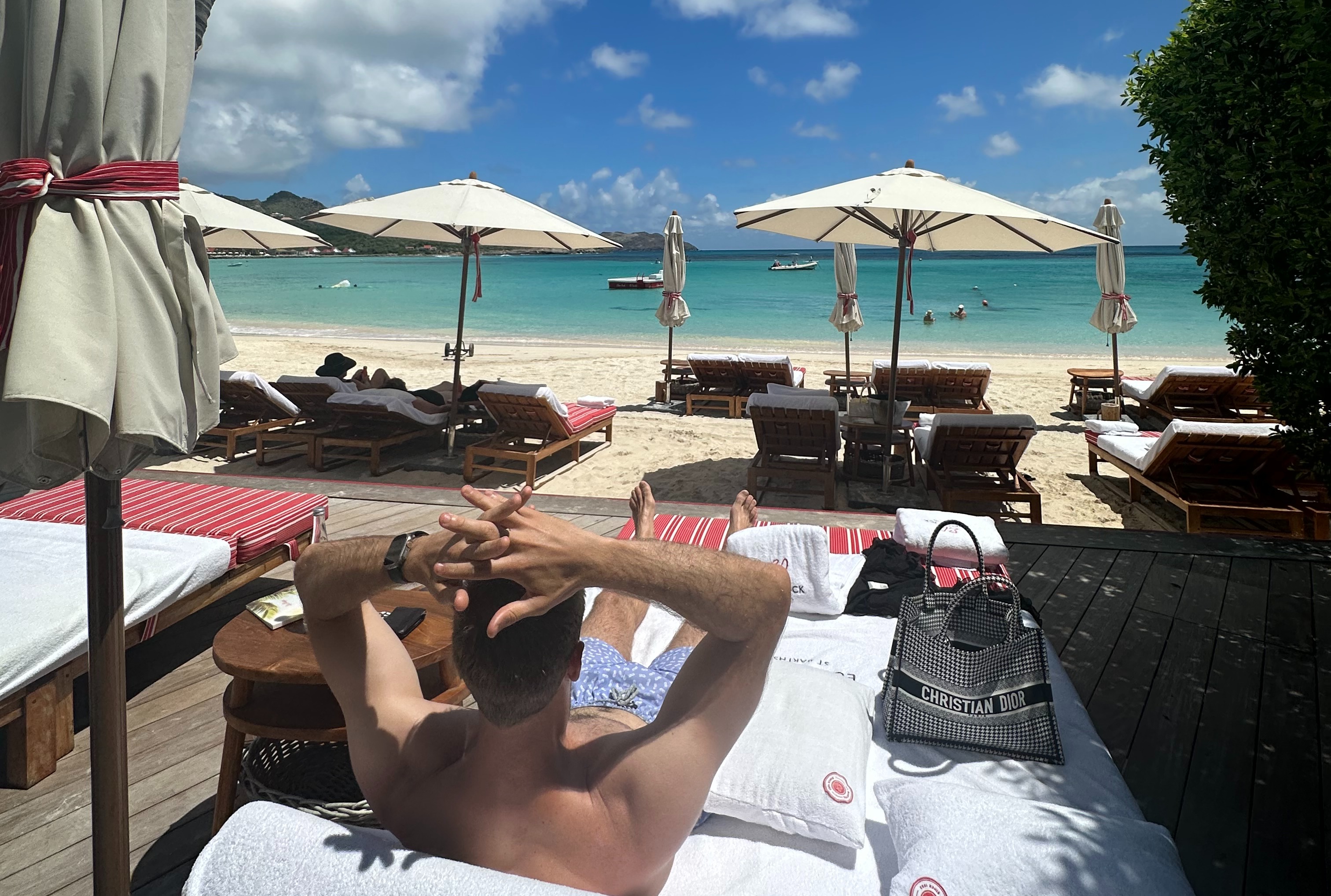 A man laying the beach bed near the beach during the daytime.