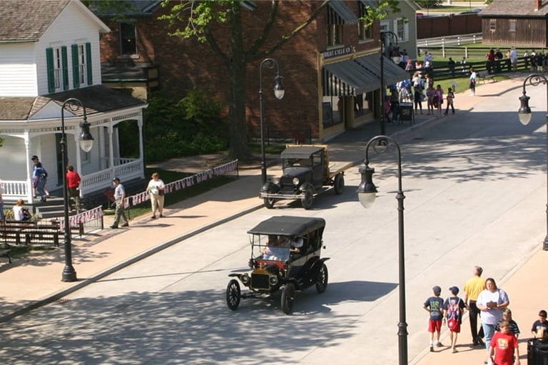Old style cars driving down a residential road