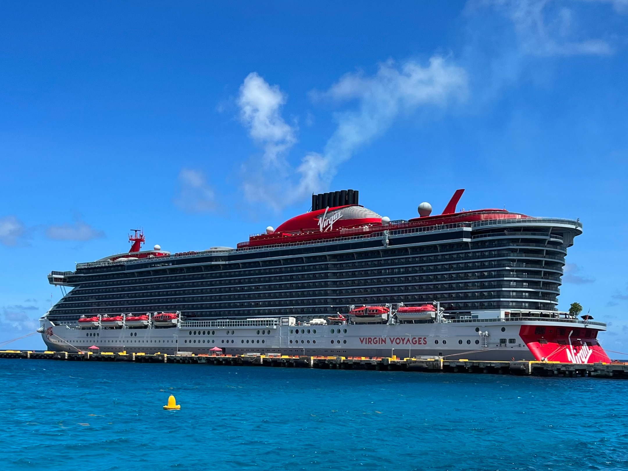 A large red cruise ship sailing on the blue water in the daytime.