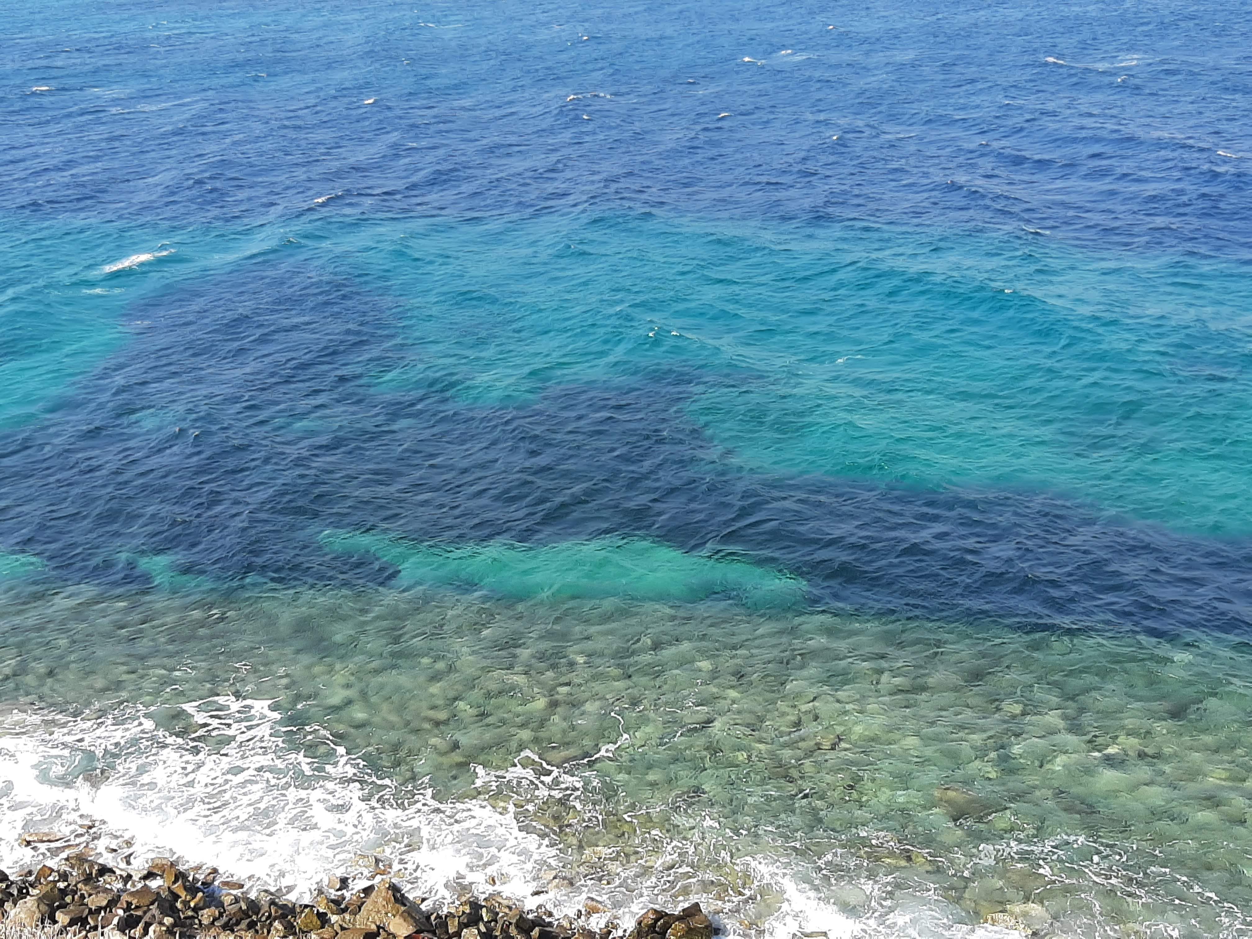 An aerial view of the blue and green water during the daytime.