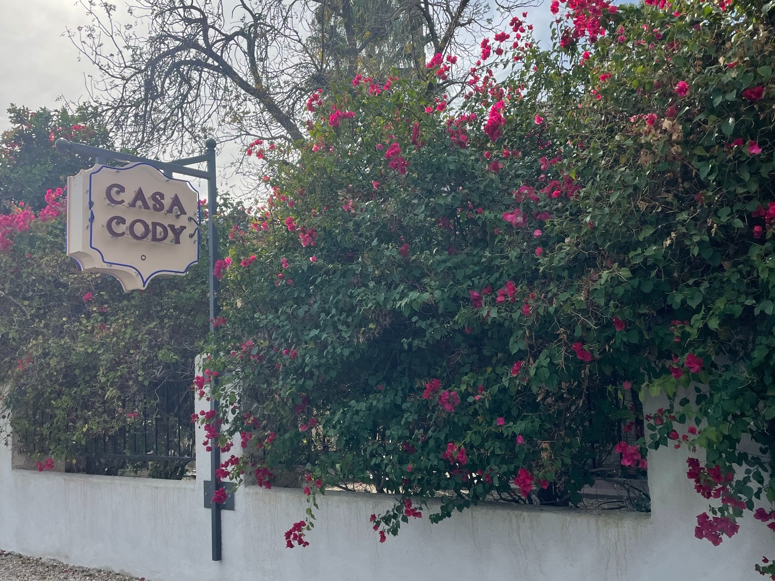 A hotel sign reading "Casa Cody" next to a flowery bush