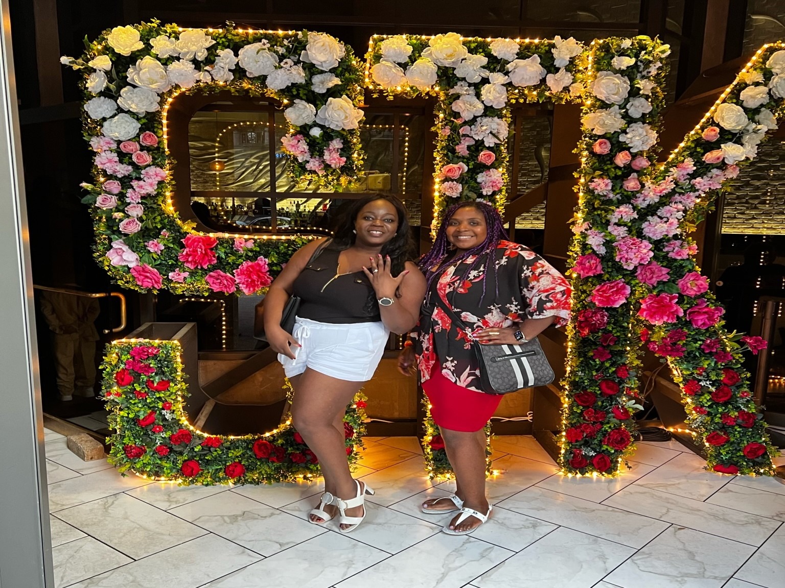 A picture of two women posing in front of STK sign.