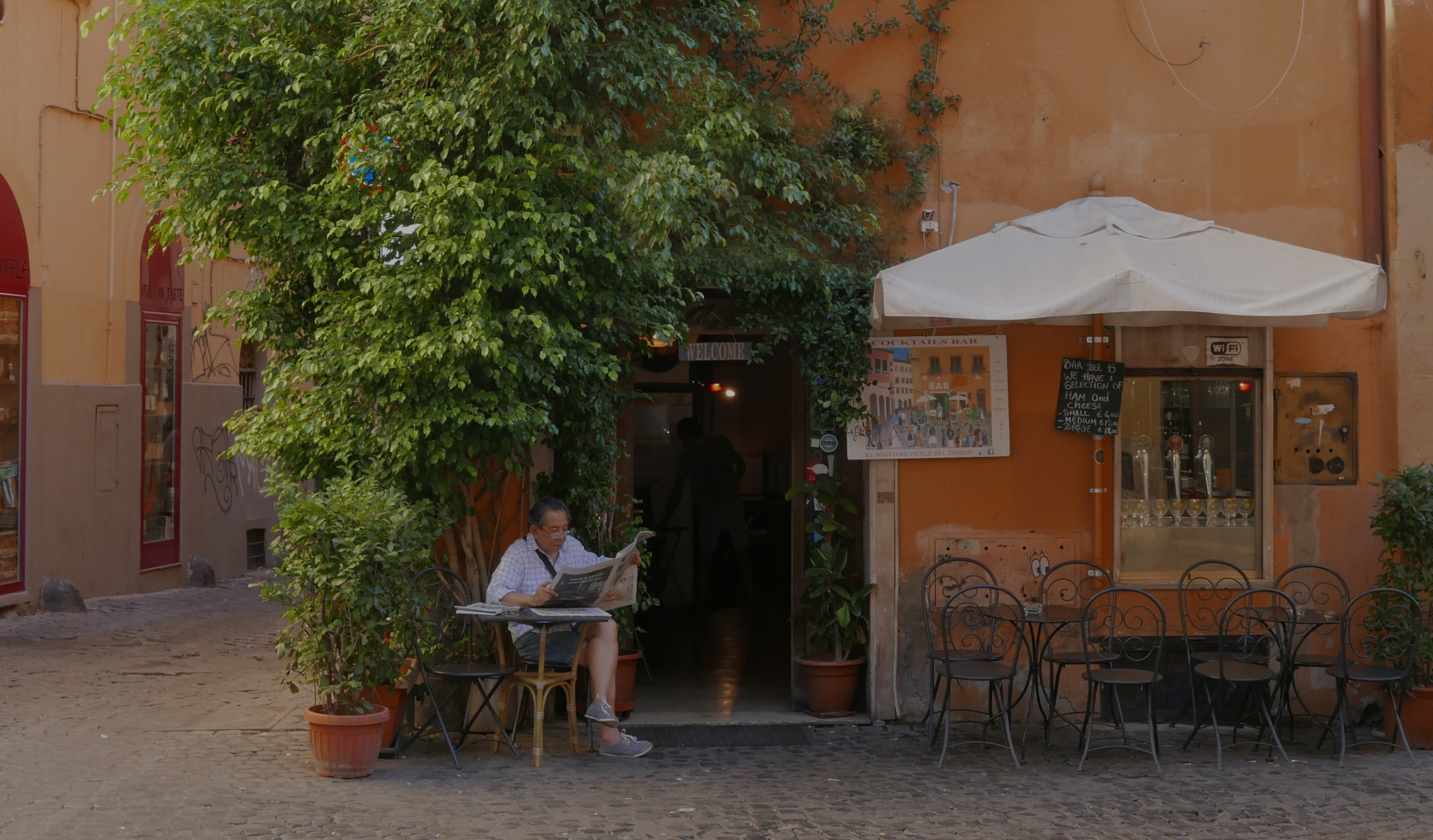 a man reads a newspaper on a cozy sidestreet