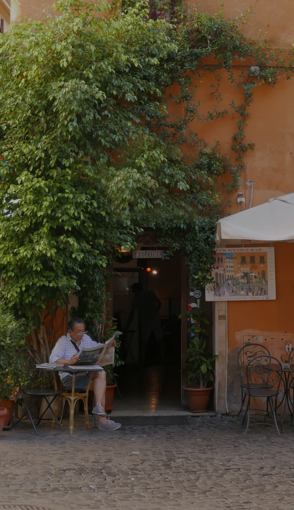 a man reads a newspaper on a cozy sidestreet