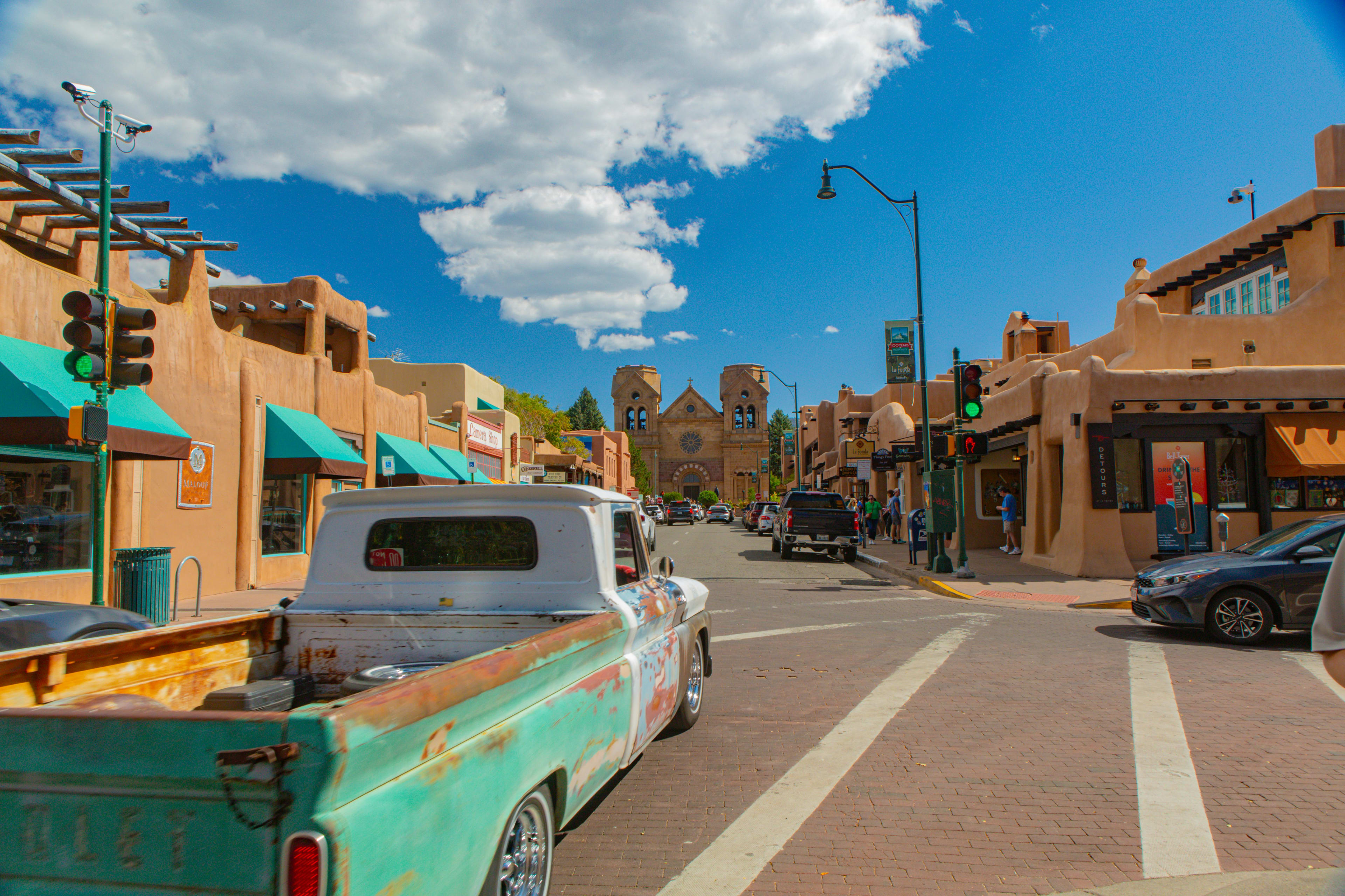 Woman posing in front of a white all with different frames and wall art saying 'Wahoo! Santa Fe'