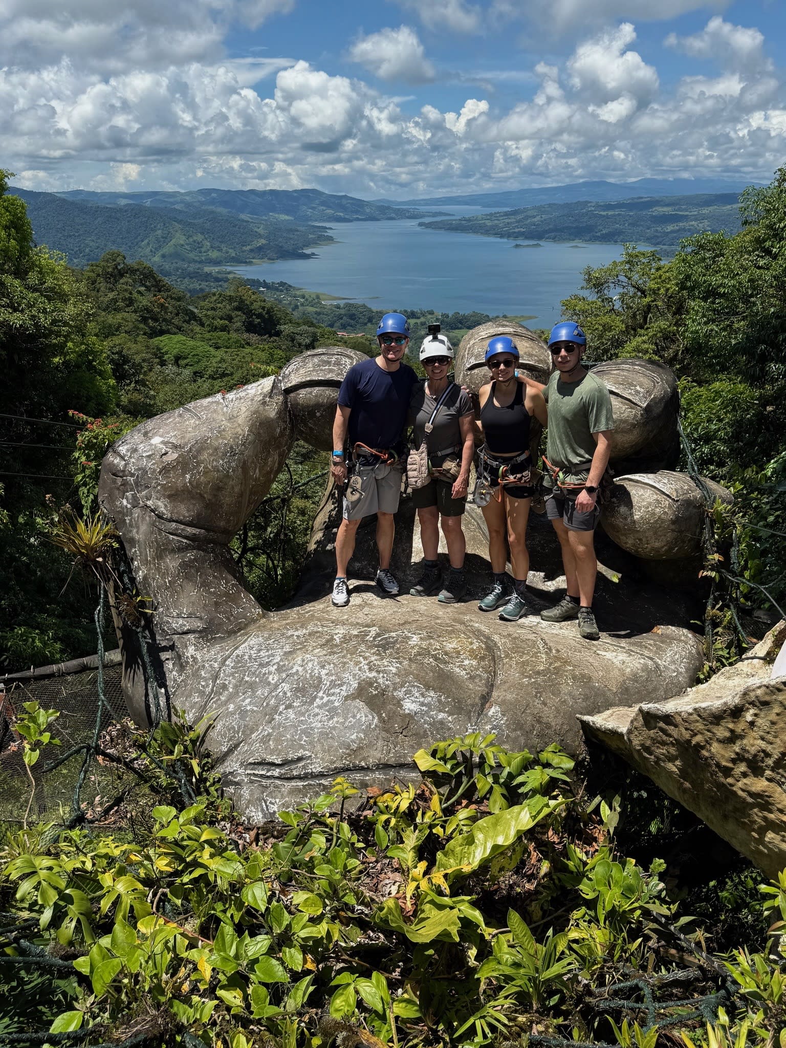 A group of people posing for a photograph together while standing on top of a statue shaped like a palm