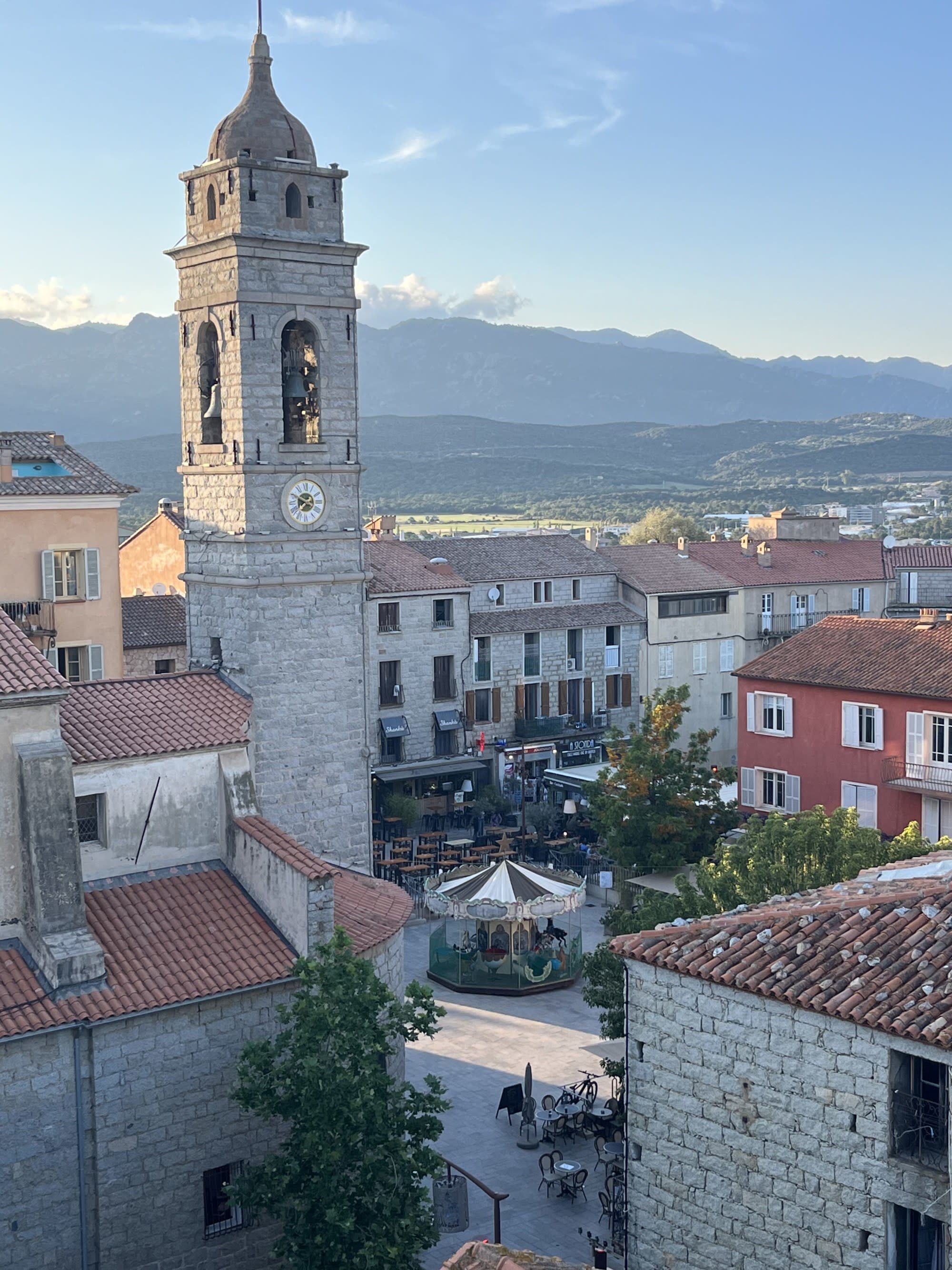 Buildings with mountains stretching toward the horizon in the distance on a sunny day.