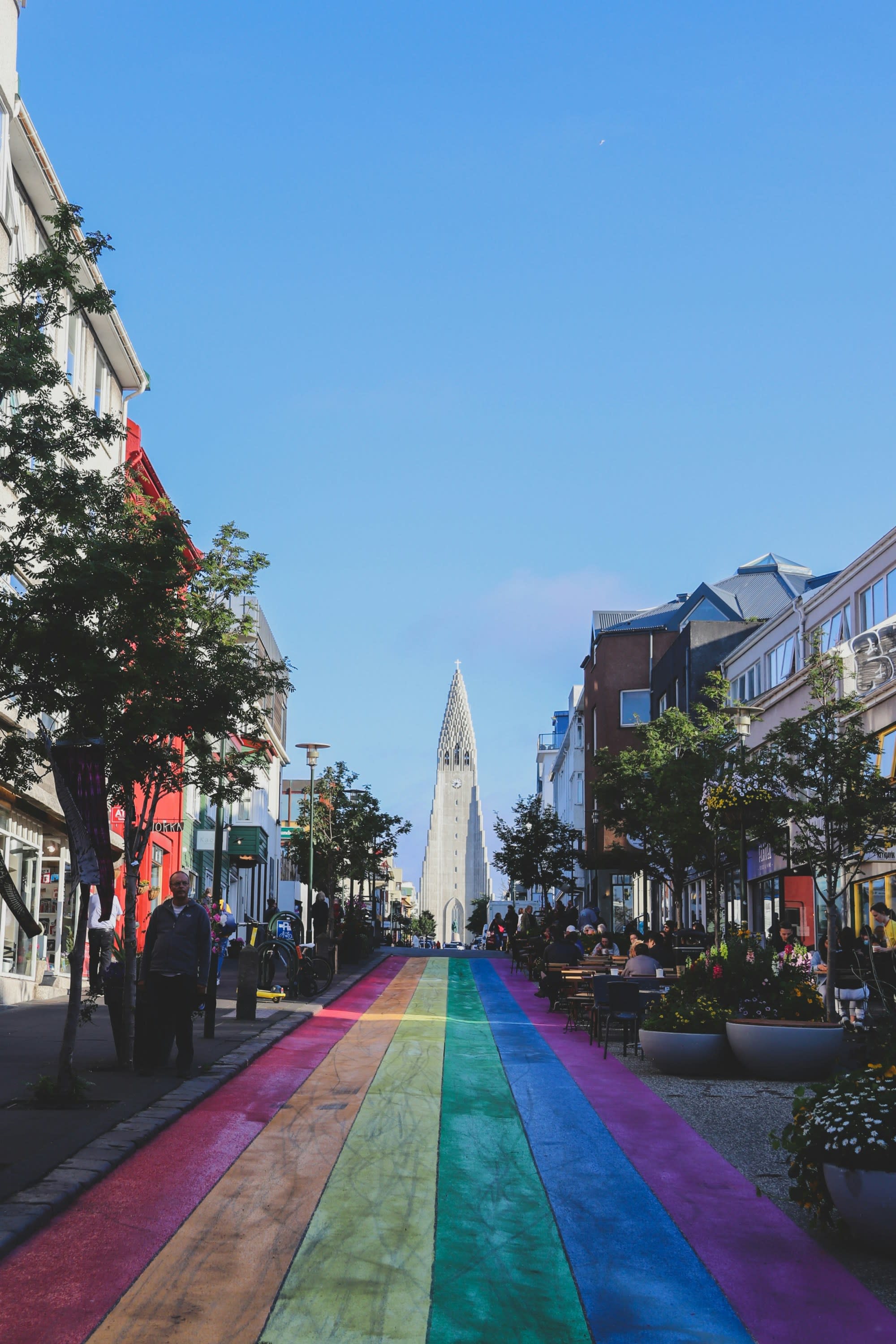 A vibrant pedestrian street with a colorful rainbow path leads towards a distinctive church in the background.