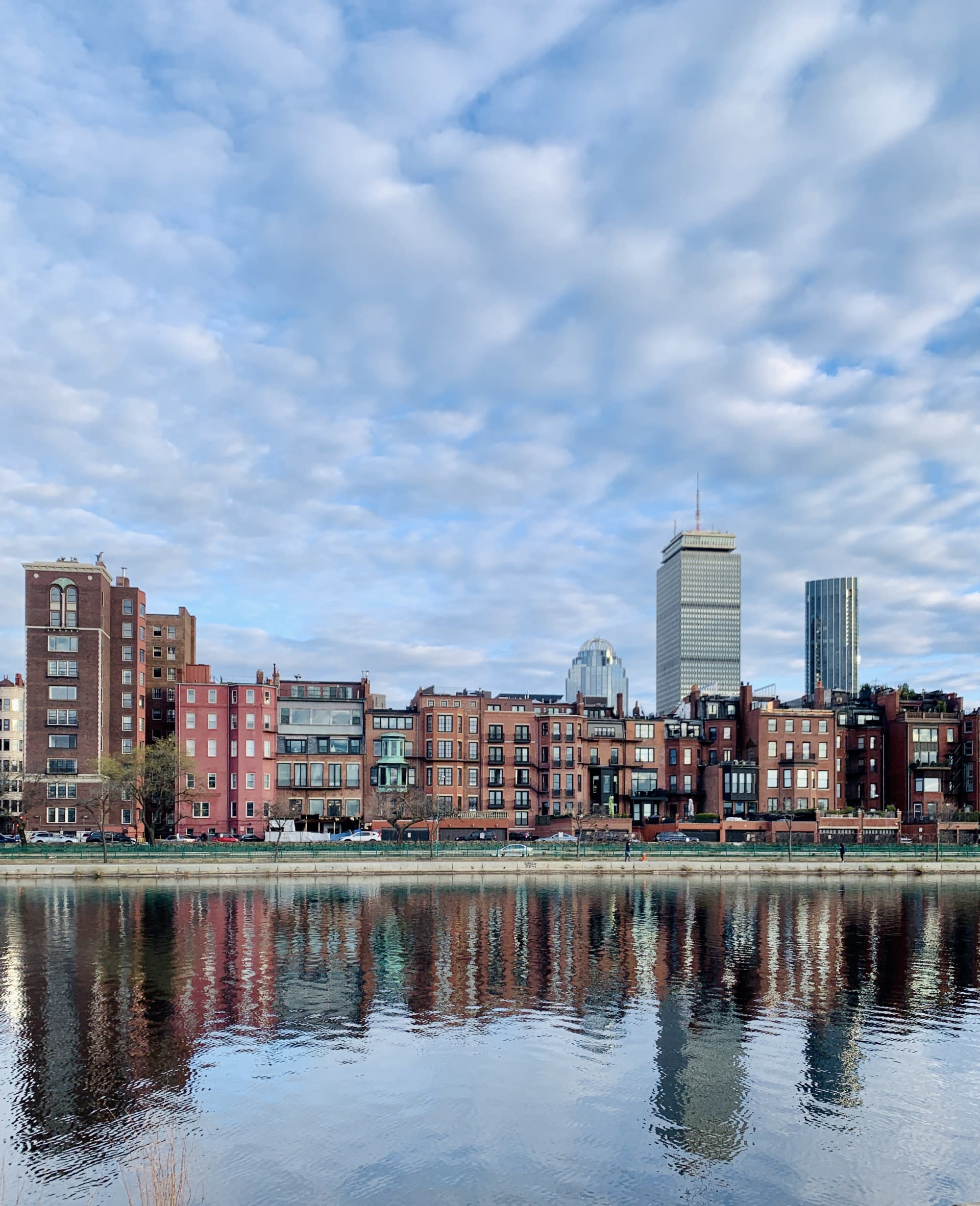 A view of the city from over the water with a cloudy sky overhead.