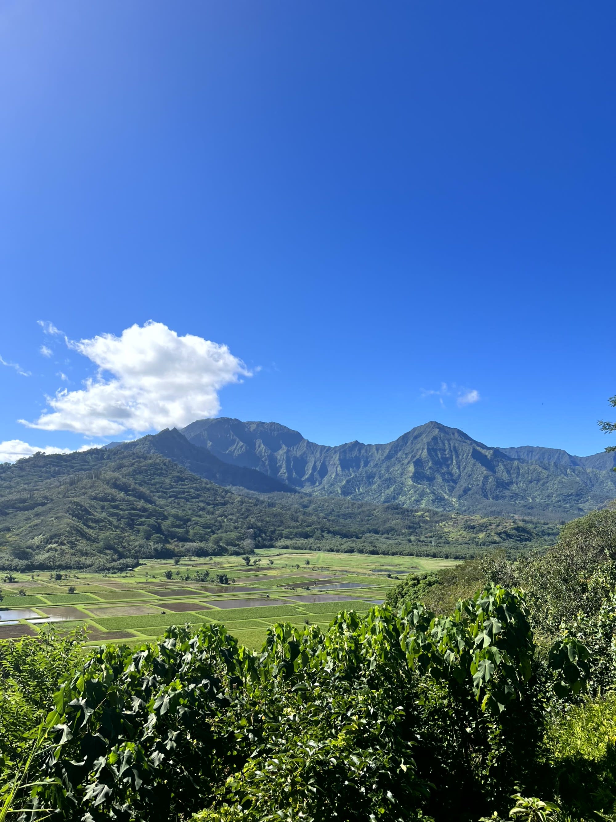 A mountain with a unique heart-shaped opening near its peak stands under a blue sky with clouds.