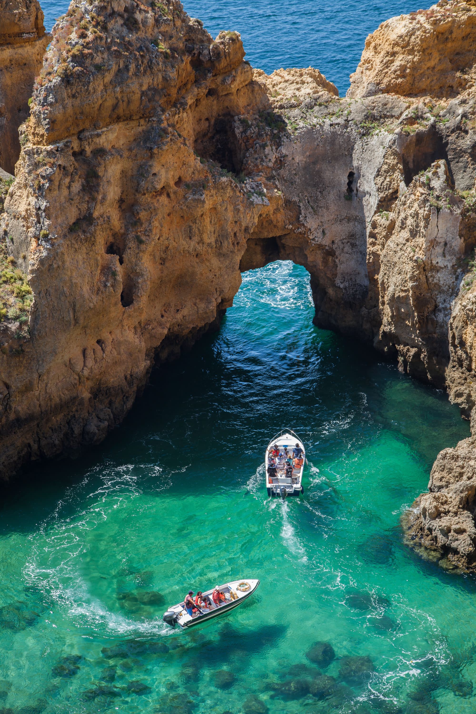 rock structure of an arch in the ocean with two boats