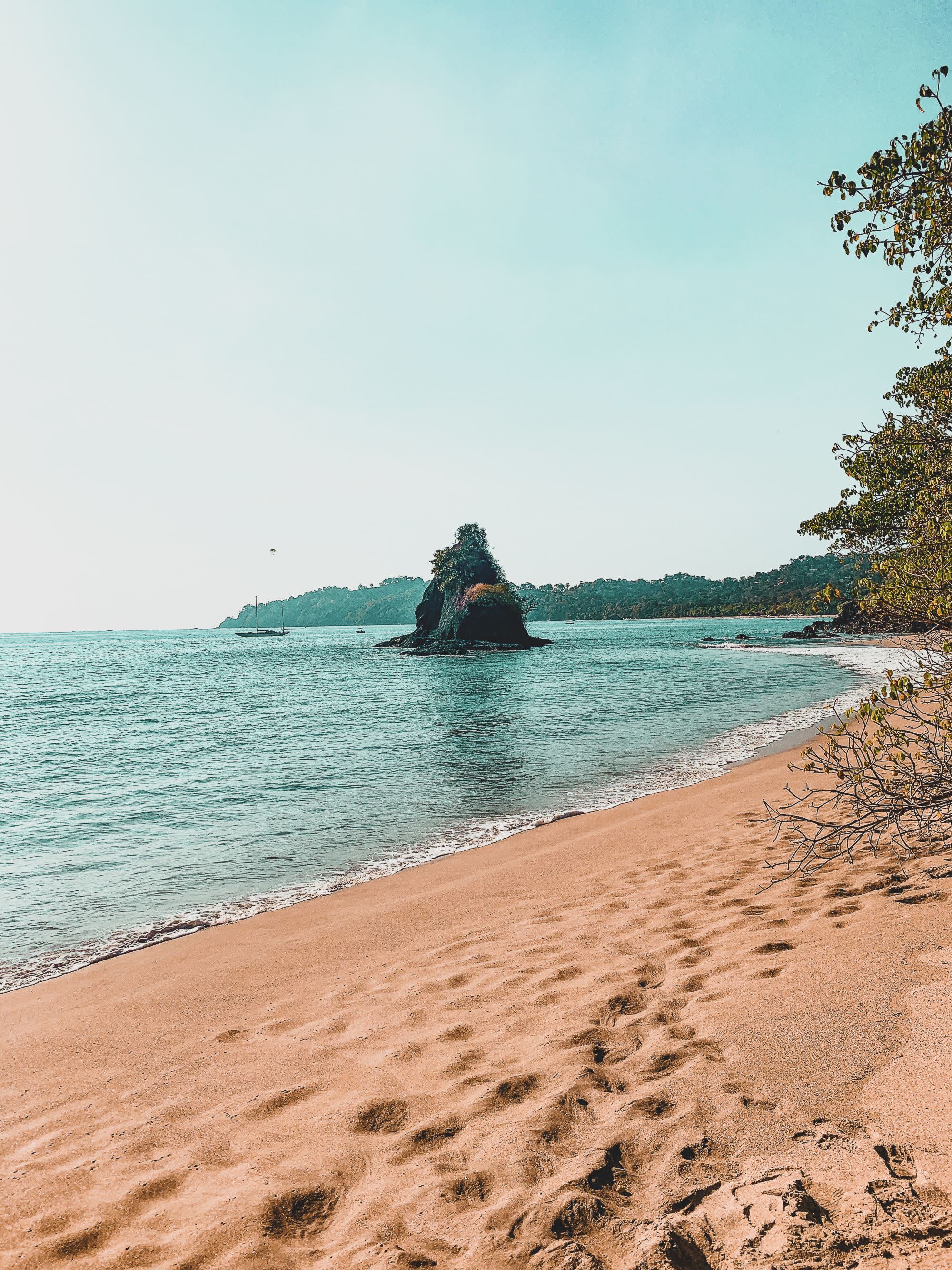 grassy rock formation jutting out from the ocean near a private beach